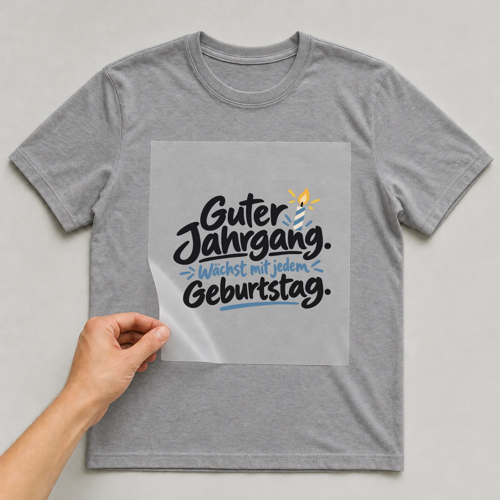 Bügelbild „Guter Jahrgang. Wächst mit jedem Geburtstag.“ auf grauem T-Shirt, Folie wird aufgelegt