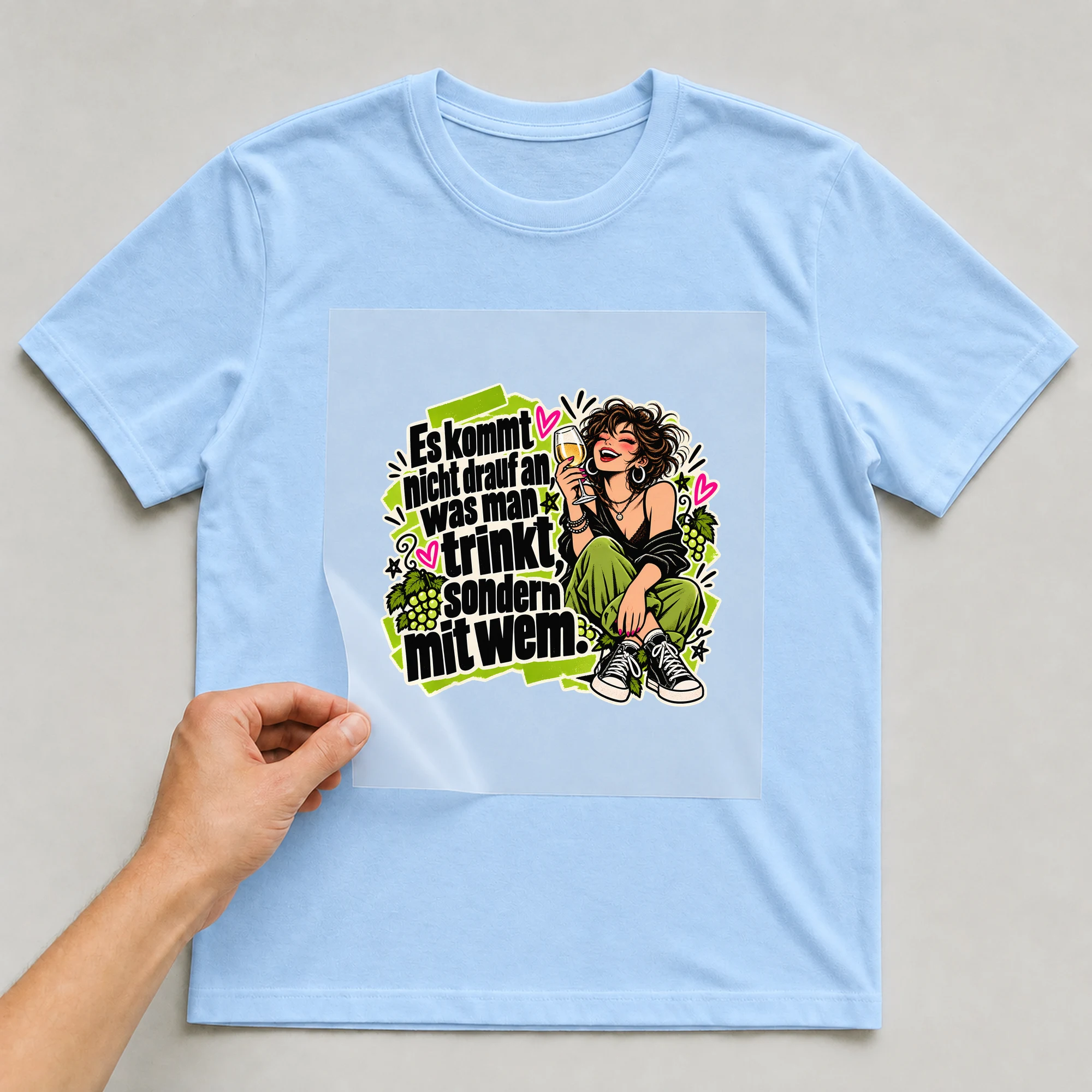Bügelbild „Es kommt nicht drauf an, was man trinkt, sondern mit wem.“ auf babyblauem T-Shirt, Folie wird aufgelegt
