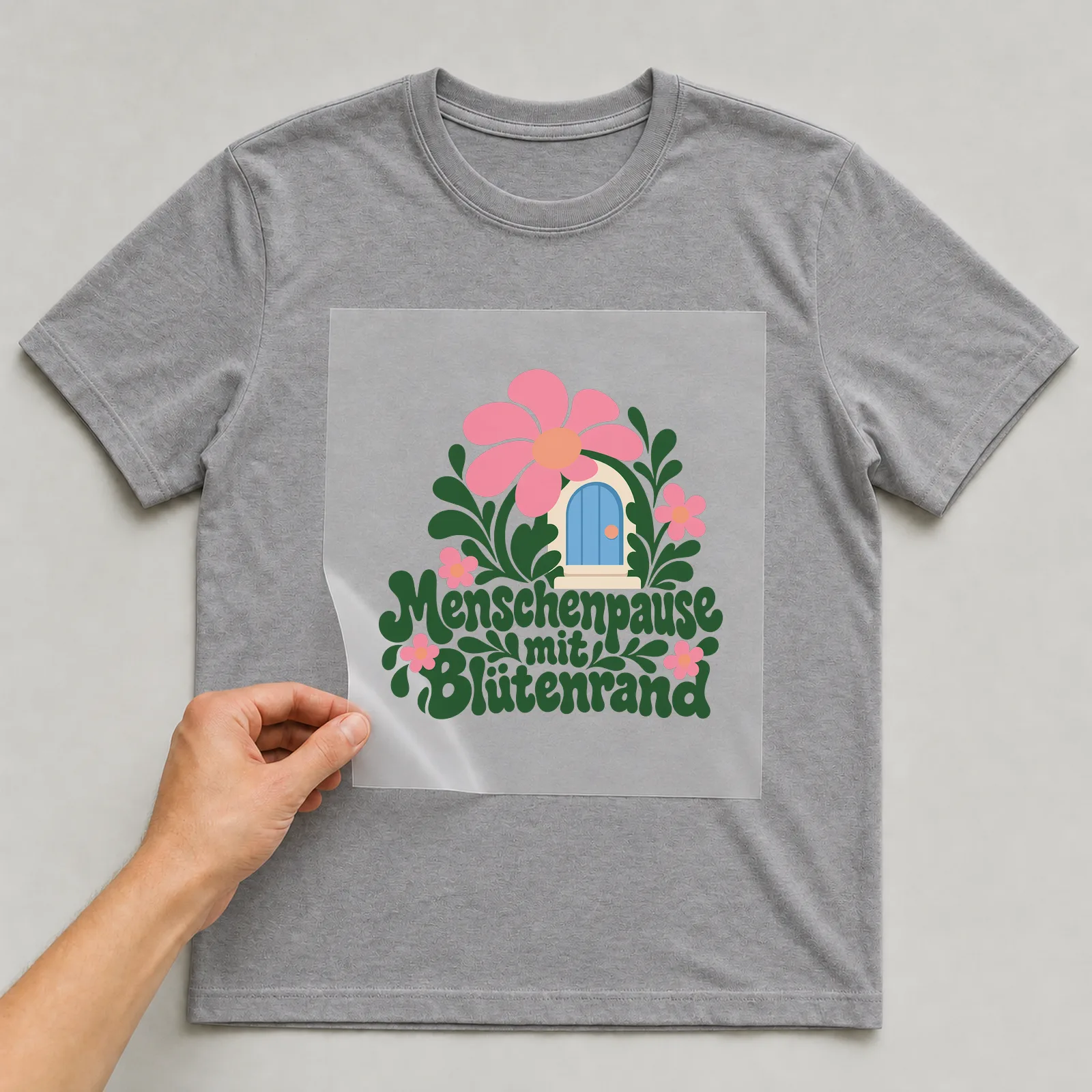 Bügelbild „Menschenpause mit Blütenrand“ auf grauem T-Shirt, Folie wird aufgelegt
