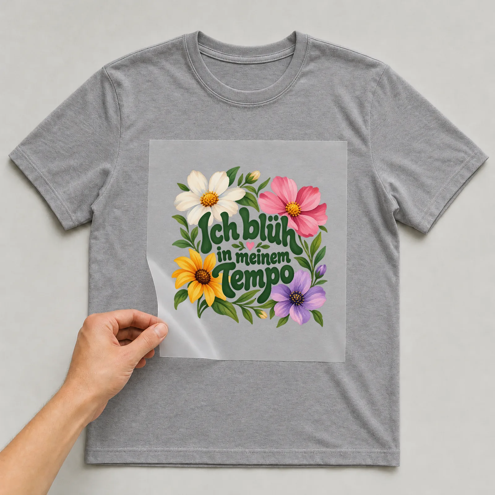 Bügelbild „Ich blüh in meinem Tempo“ auf grauem T-Shirt, Folie wird aufgelegt