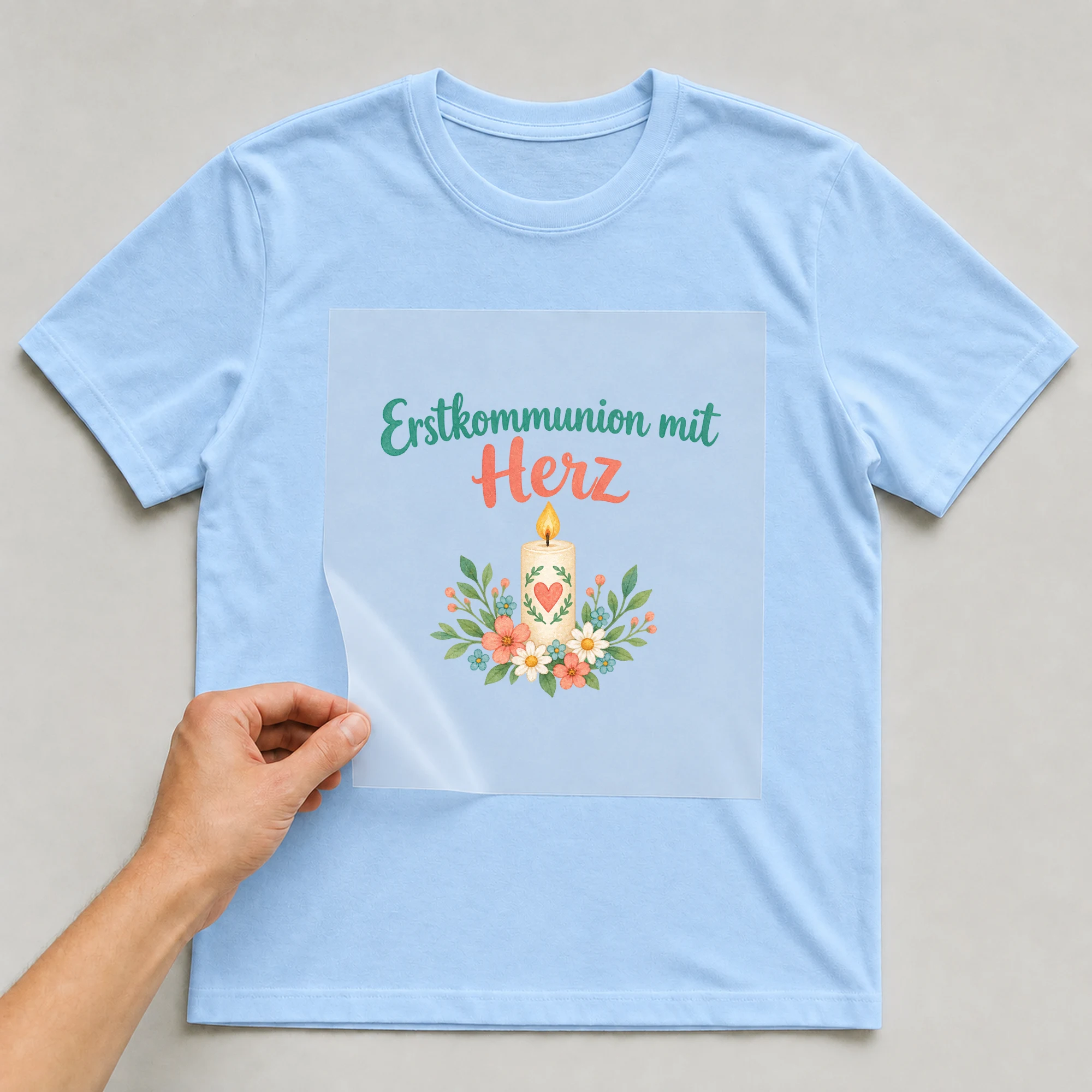 Bügelbild „Erstkommunion mit Herz“ auf babyblauem T-Shirt, Folie wird aufgelegt