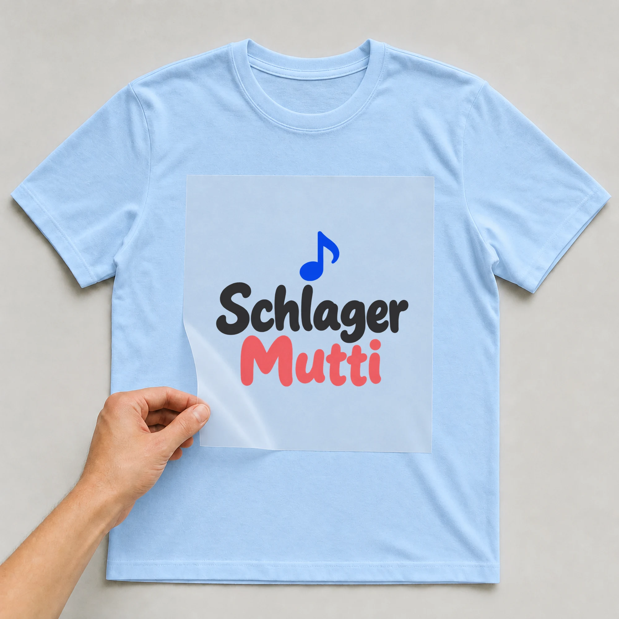 Bügelbild „Schlager Mutti“ auf babyblauem T-Shirt, Folie wird aufgelegt
