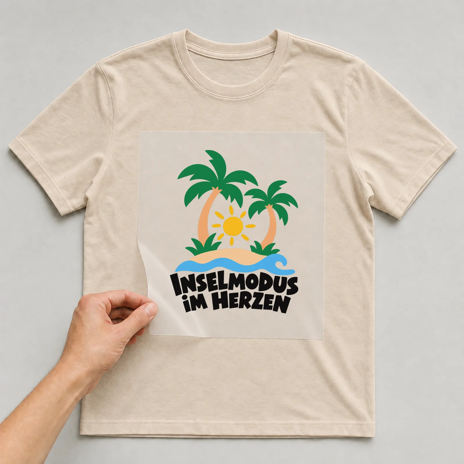 Bügelbild „Inselmodus im Herzen“ auf beigem T-Shirt, Folie wird aufgelegt