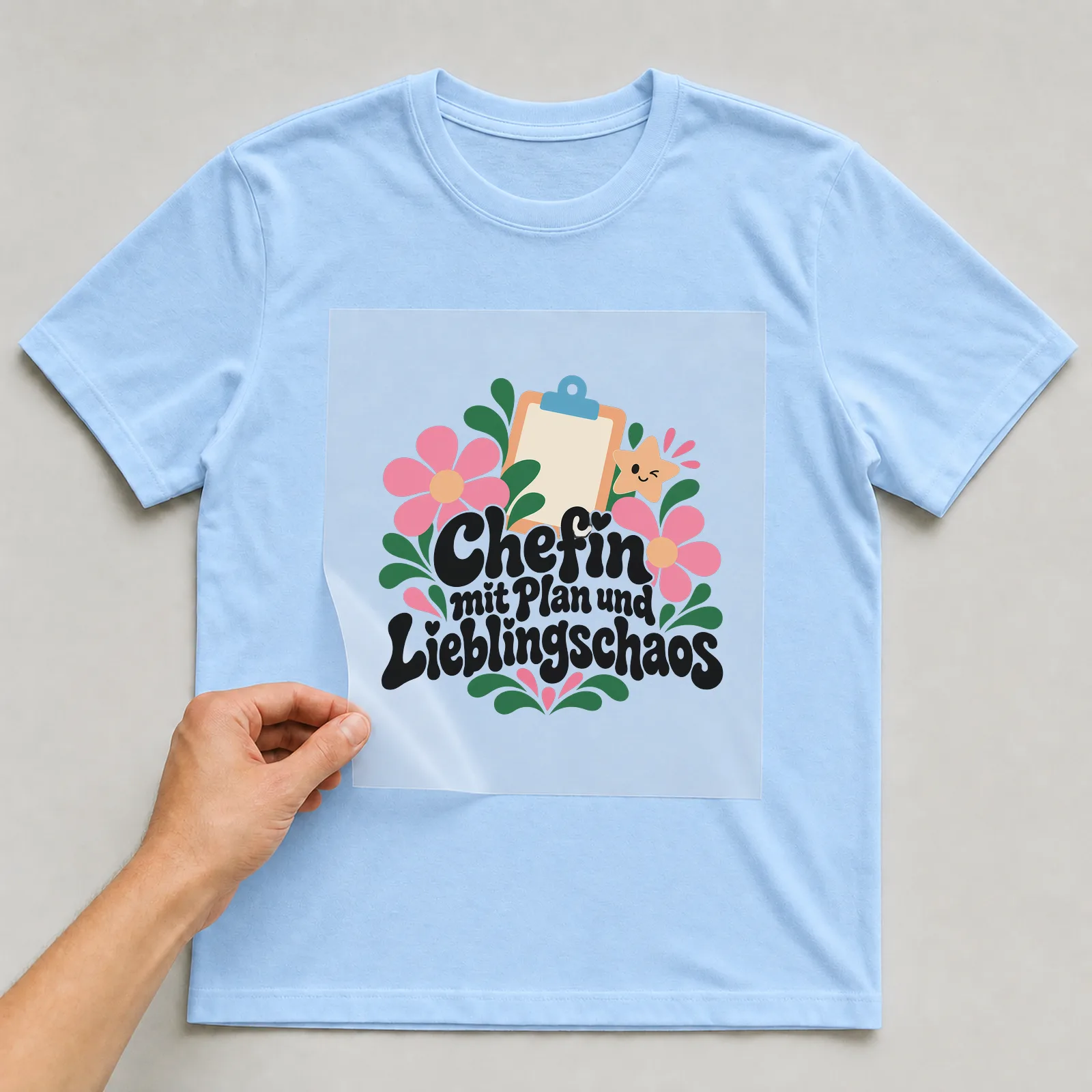 Bügelbild „Chefin mit Plan und Lieblingschaos“ auf hellblauem T-Shirt, Folie wird aufgelegt