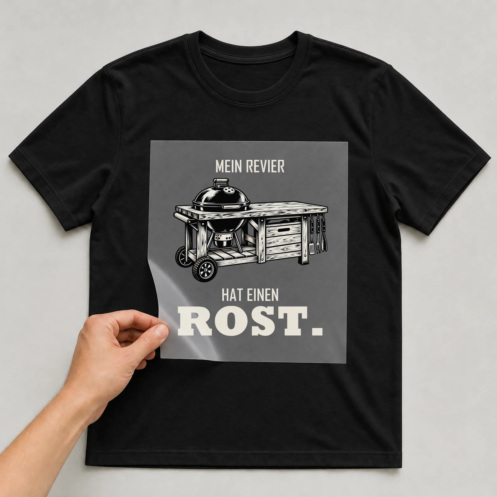 Bügelbild „Mein Revier hat einen Rost“ auf schwarzem T-Shirt, Folie wird aufgelegt