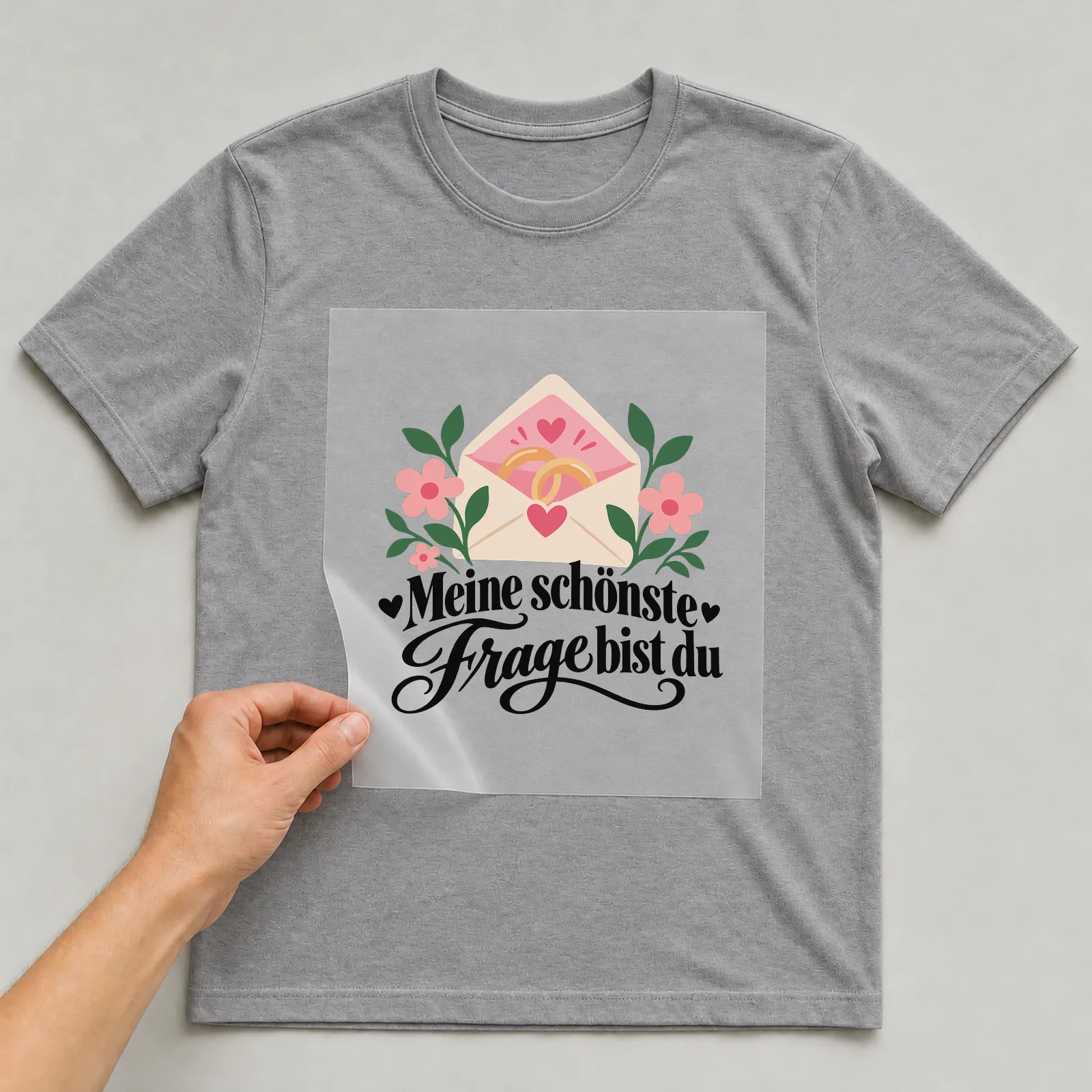 Bügelbild „Meine schönste Frage bist du“ auf grauem T-Shirt, Folie wird aufgelegt