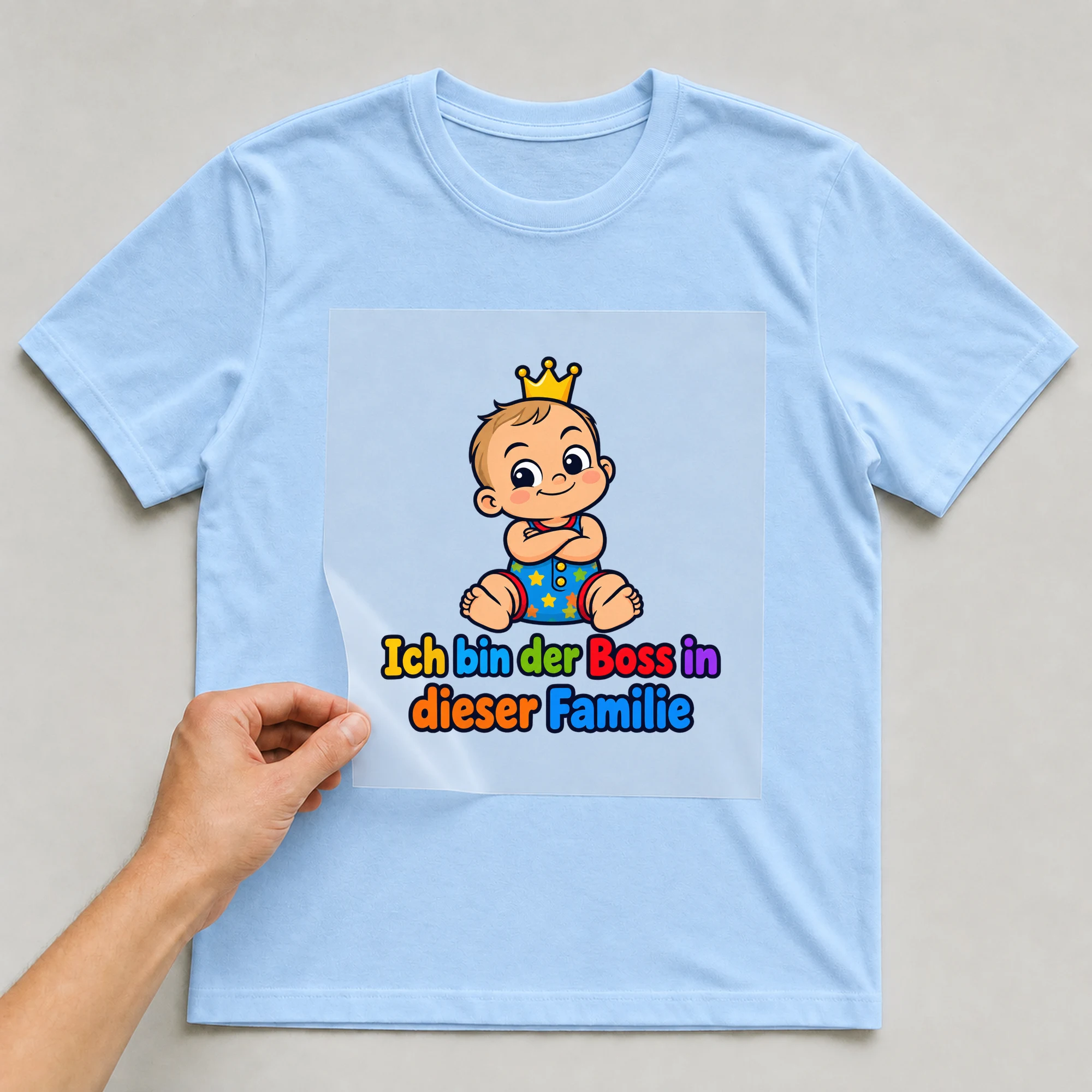 Bügelbild „Ich bin der Boss in dieser Familie“ auf babyblauem T-Shirt, Folie wird aufgelegt