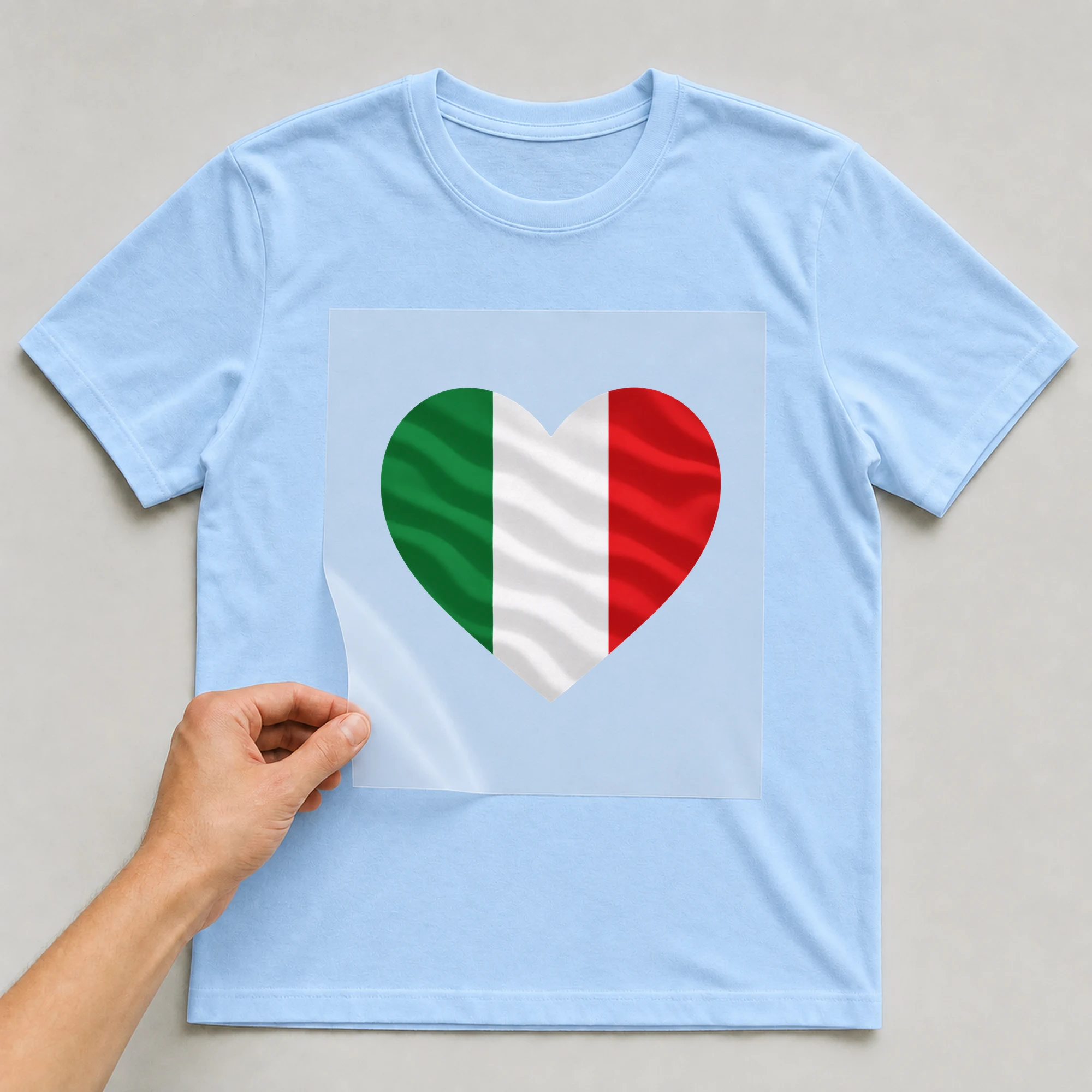 Bügelbild „Herz-Flagge Italien“ auf babyblauem T-Shirt, Folie wird aufgelegt
