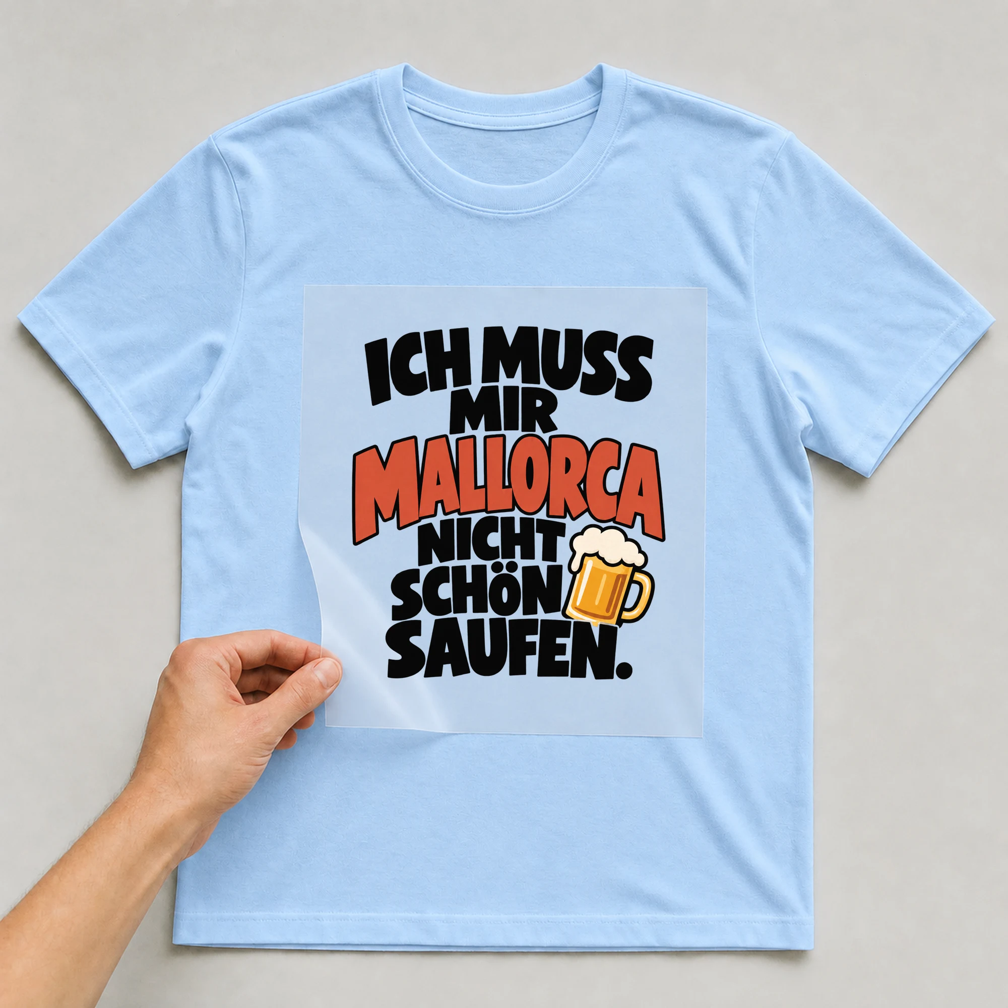 Bügelbild „Ich muss mir Mallorca nicht schön saufen.“ auf babyblauem T-Shirt, Folie wird aufgelegt