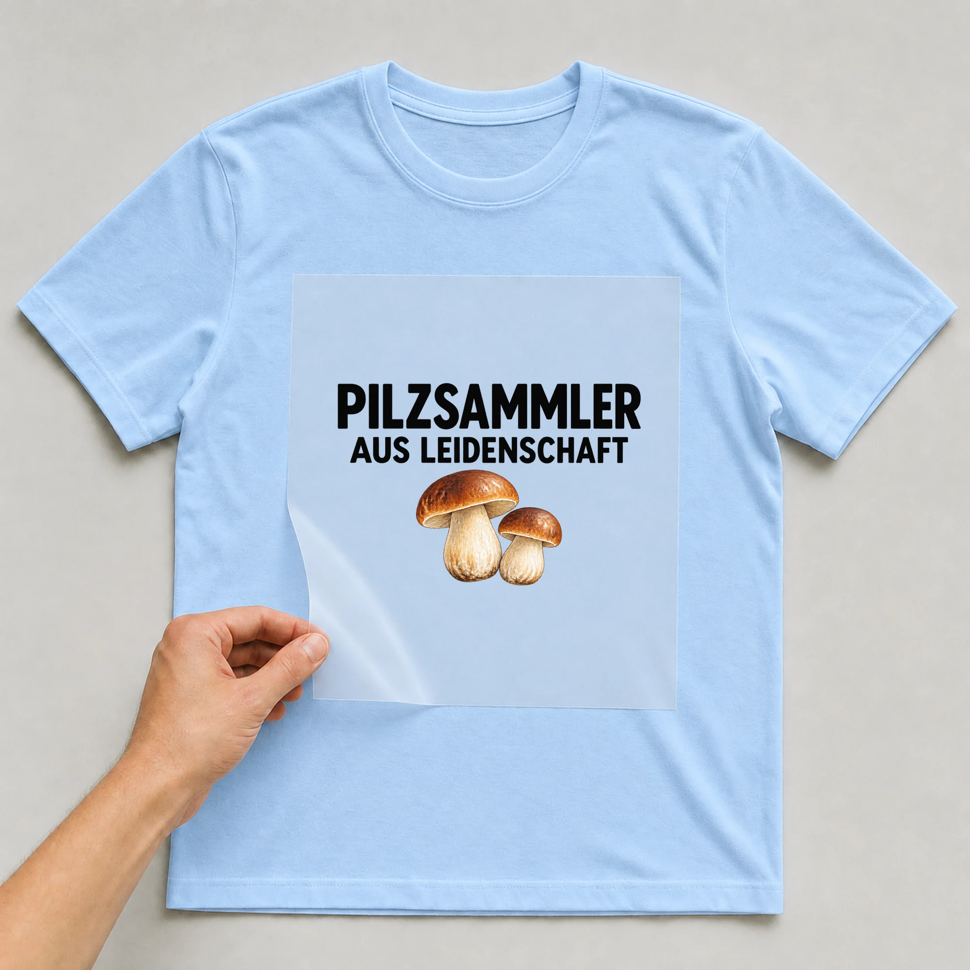 Bügelbild „Pilzsammler Aus Leidenschaft“ auf babyblauem T-Shirt, Folie wird aufgelegt