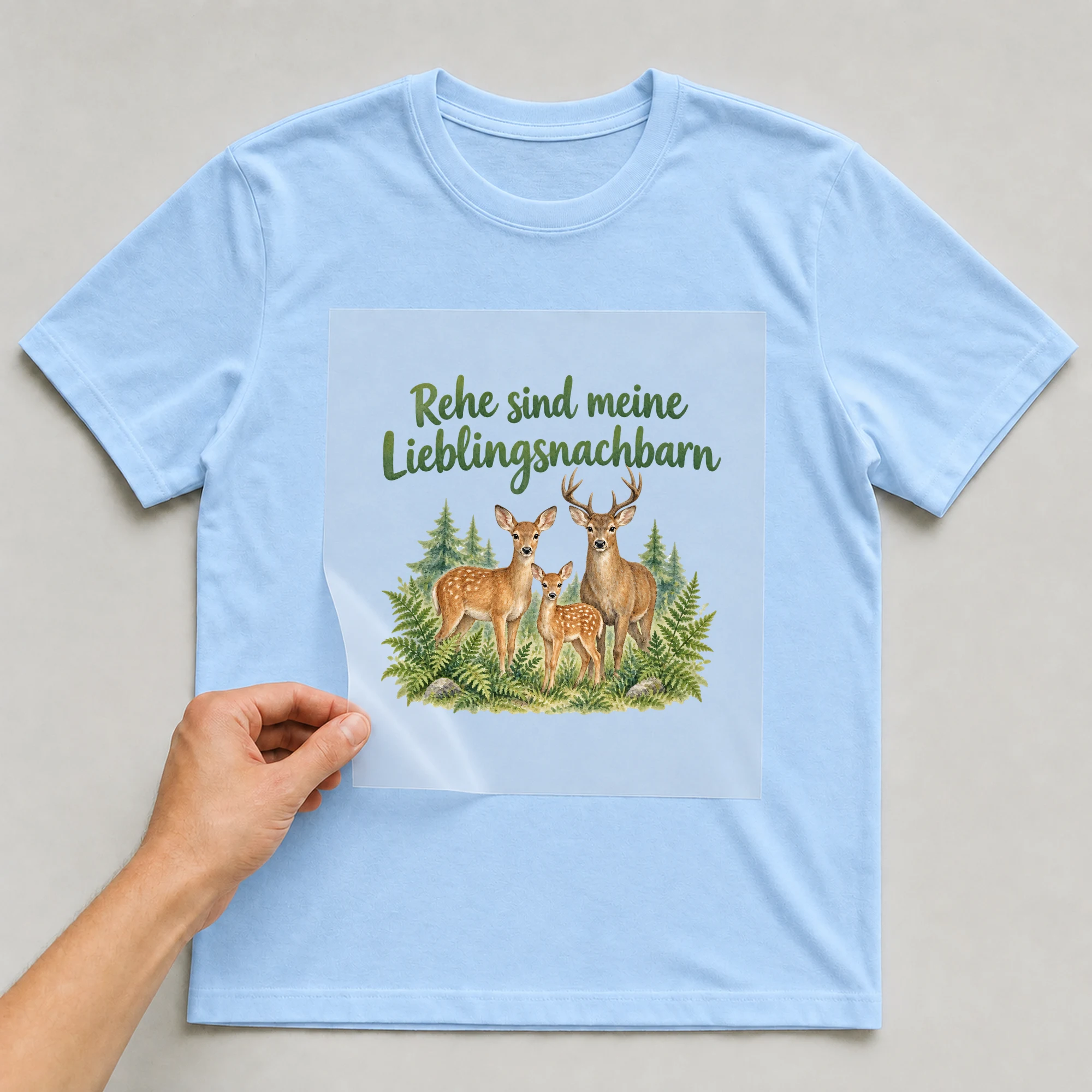 Bügelbild „Rehe sind meine Lieblingsnachbarn“ auf babyblauem T-Shirt, Folie wird aufgelegt