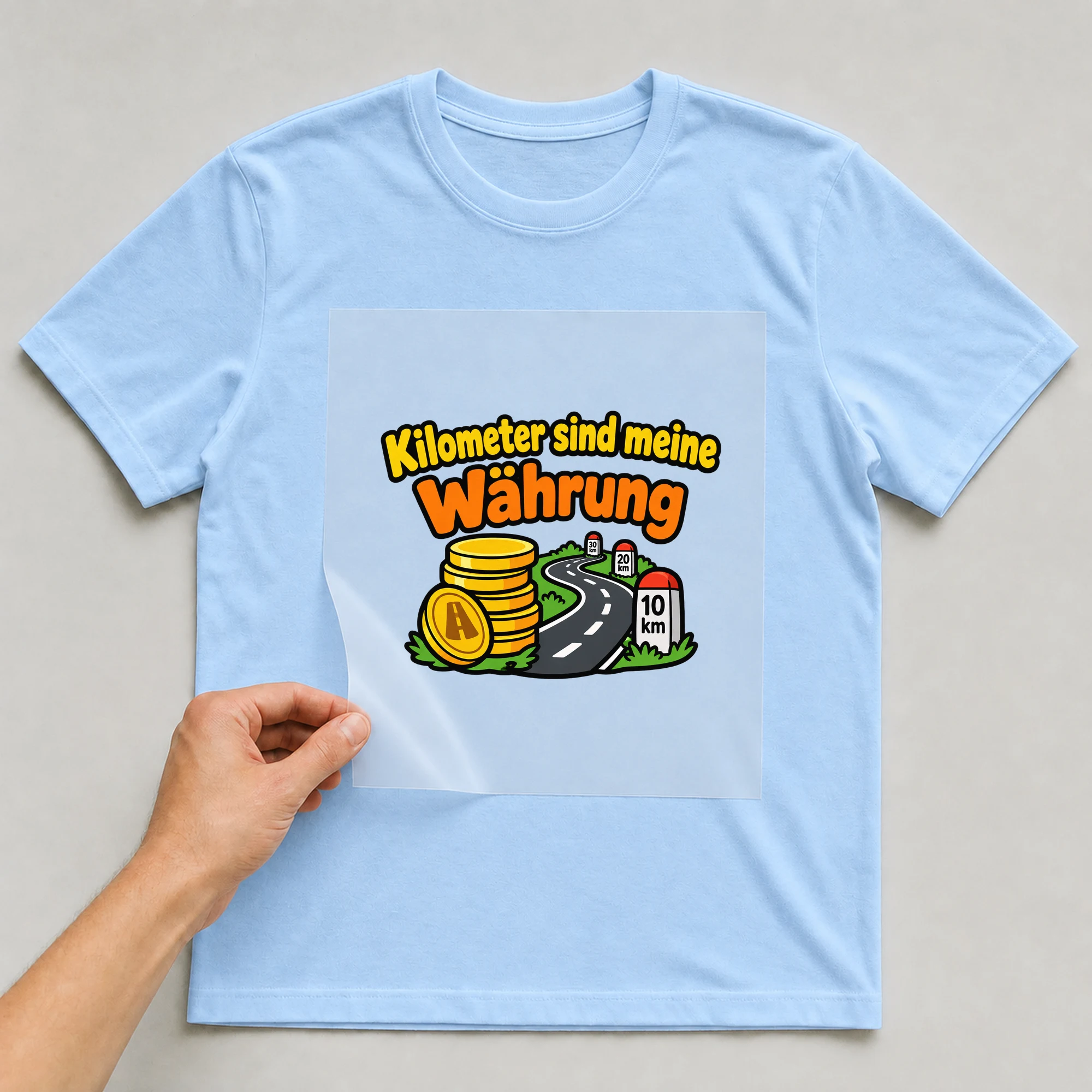 Bügelbild „Kilometer sind meine Währung“ auf babyblauem T-Shirt, Folie wird aufgelegt