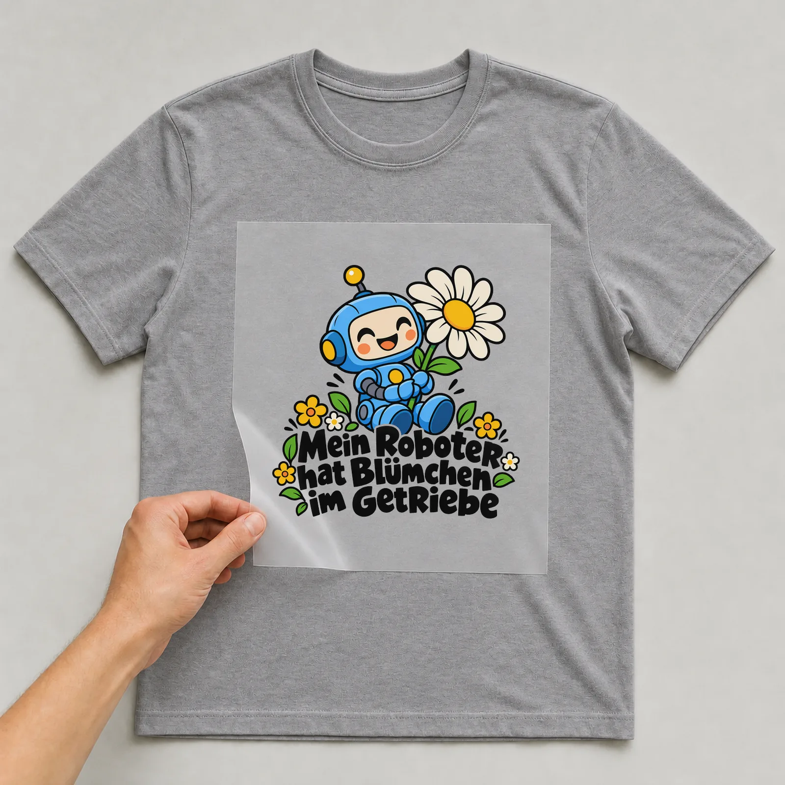Bügelbild „Mein Roboter hat Blümchen im Getriebe“ auf grauem T-Shirt, Folie wird aufgelegt