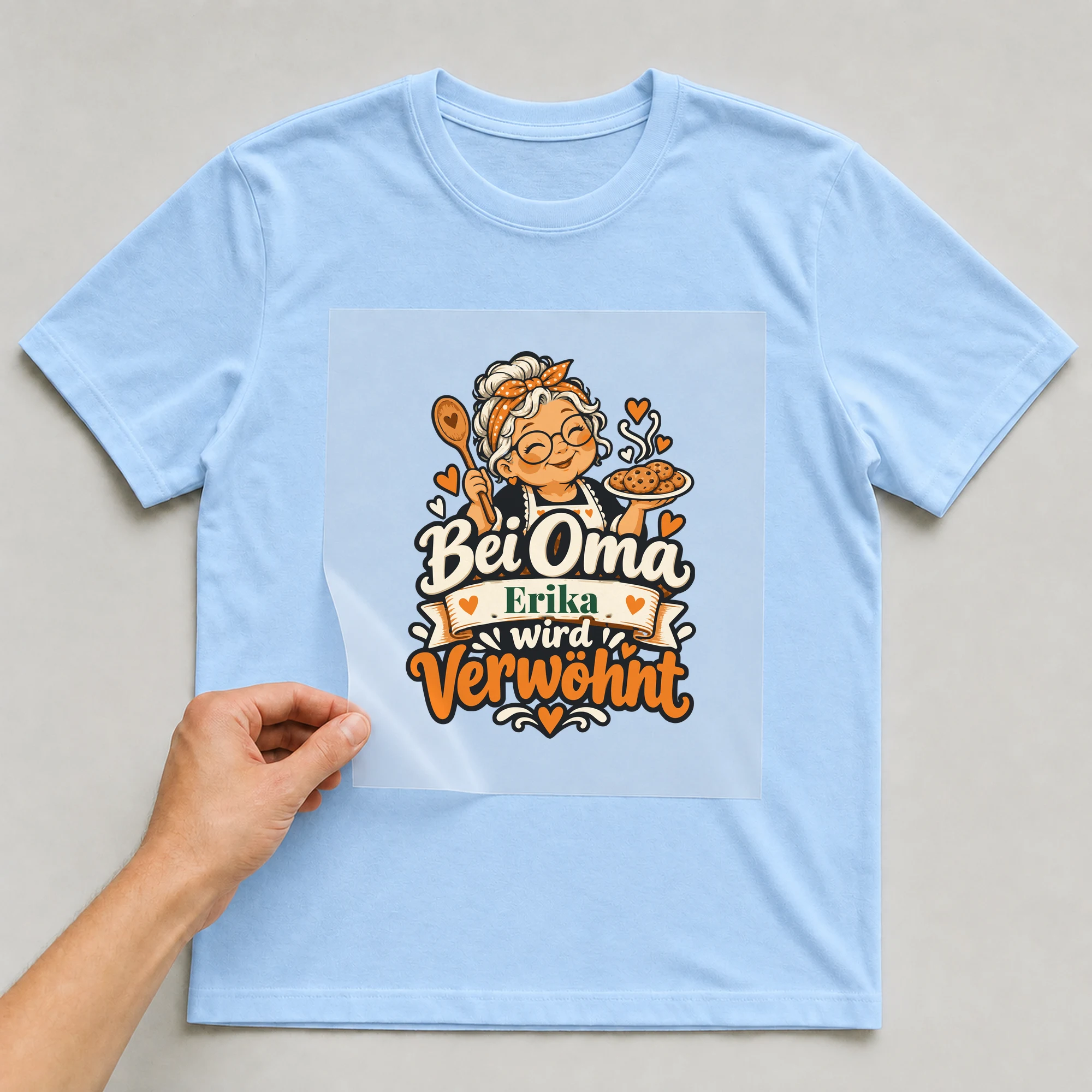 Bügelbild Bei Oma wird verwöhnt mit Name auf hellblauem T-Shirt, Folie wird aufgelegt