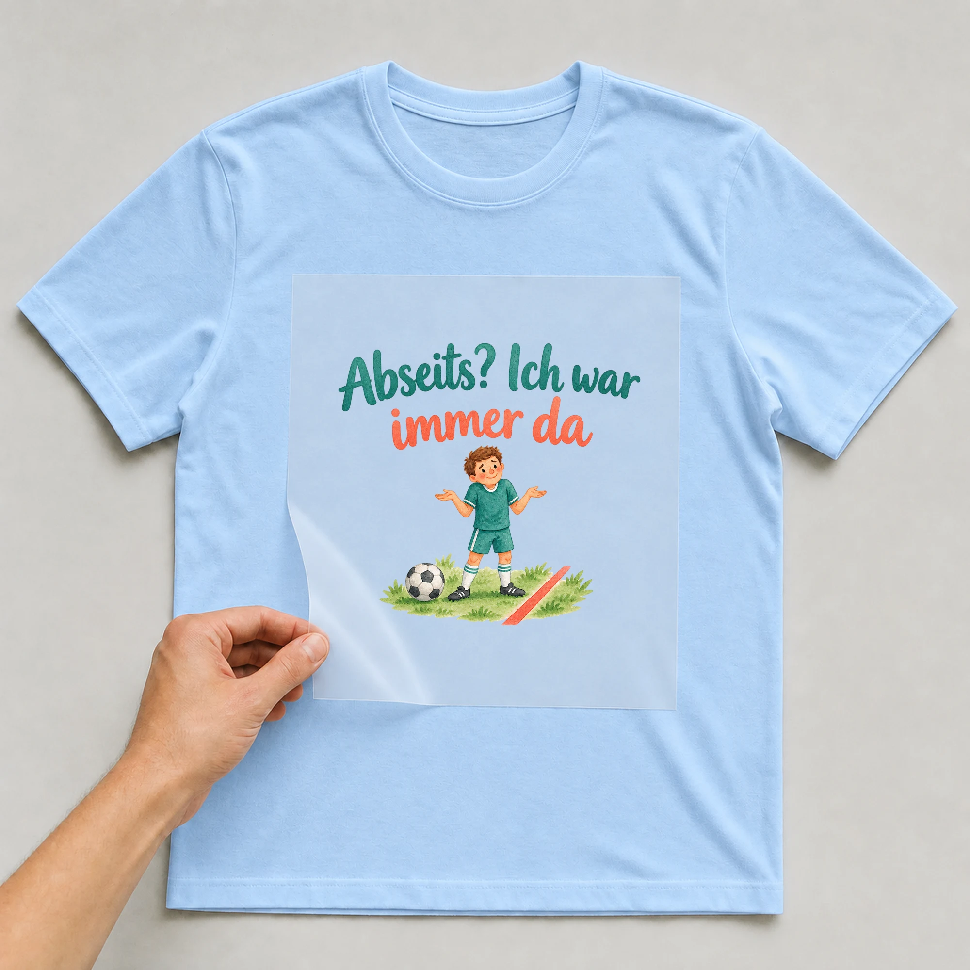 Bügelbild „Abseits? Ich war immer da“ auf babyblauem T-Shirt, Folie wird aufgelegt
