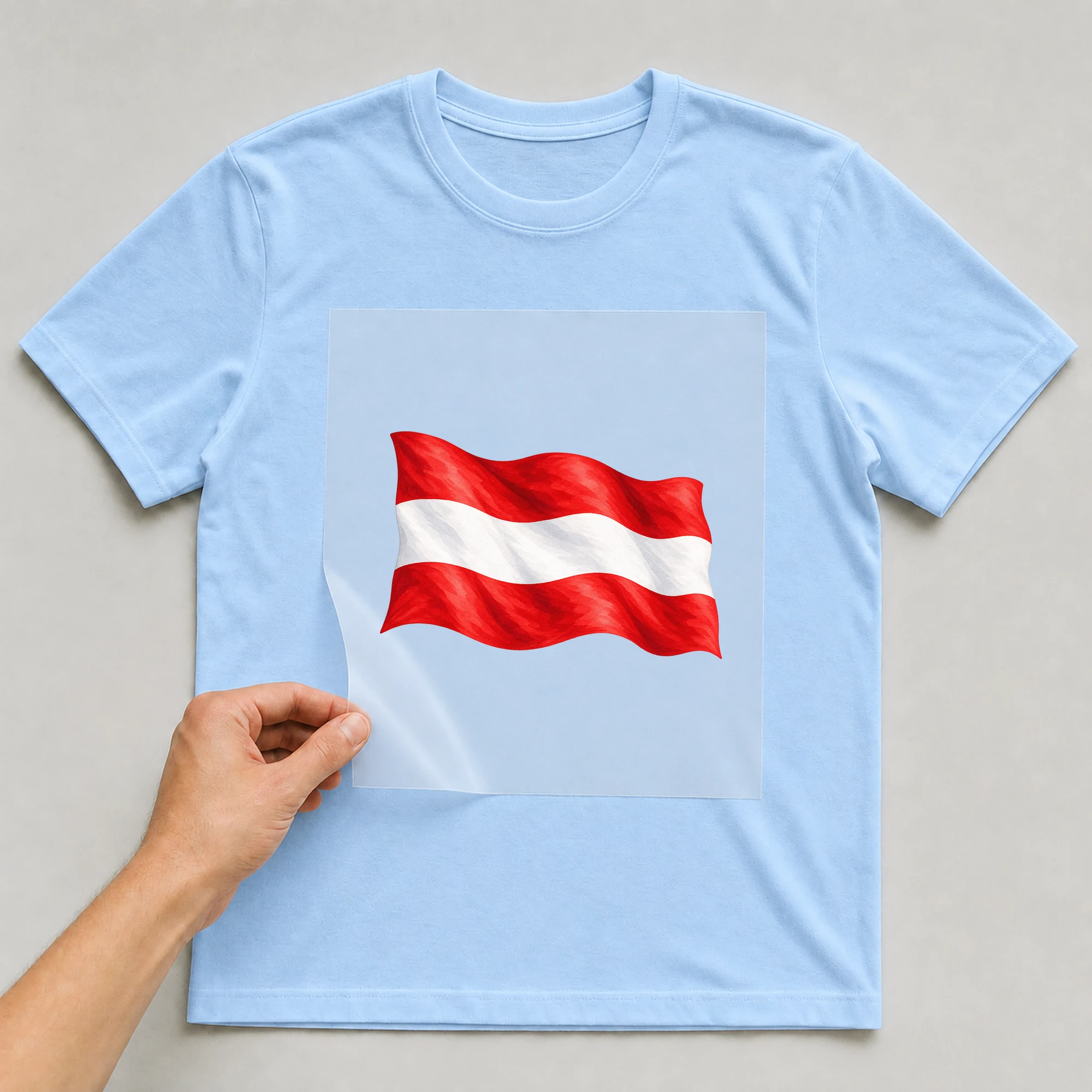 Bügelbild „Flagge Österreich“ auf babyblauem T-Shirt, Folie wird aufgelegt