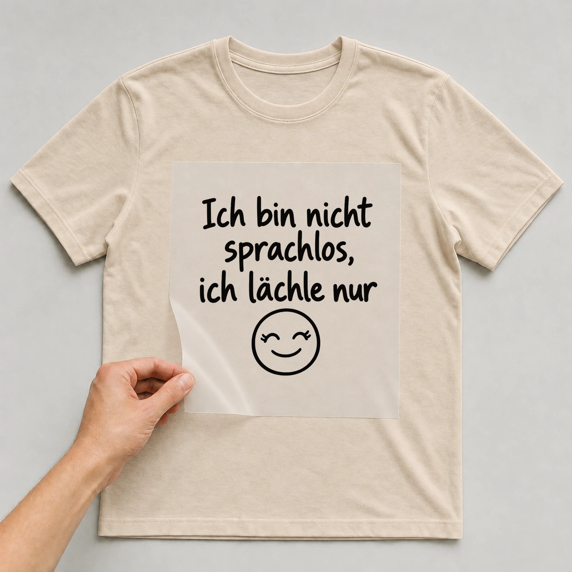Bügelbild „Ich bin nicht sprachlos, ich lächle nur“ auf beigem T-Shirt, Folie wird aufgelegt