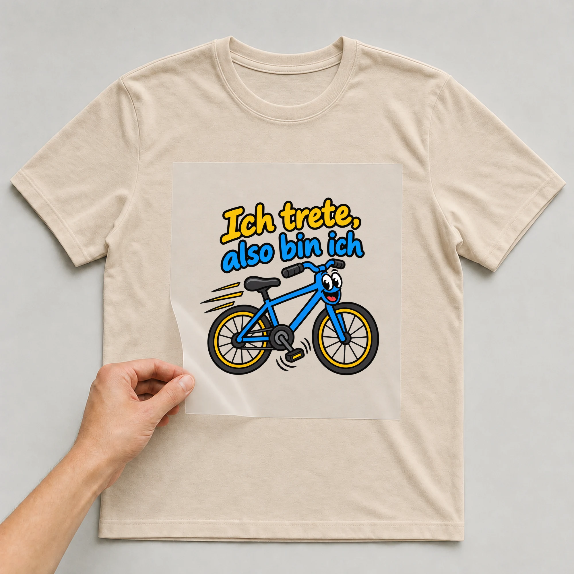 Bügelbild „Ich trete, also bin ich“ auf beigem T-Shirt, Folie wird aufgelegt