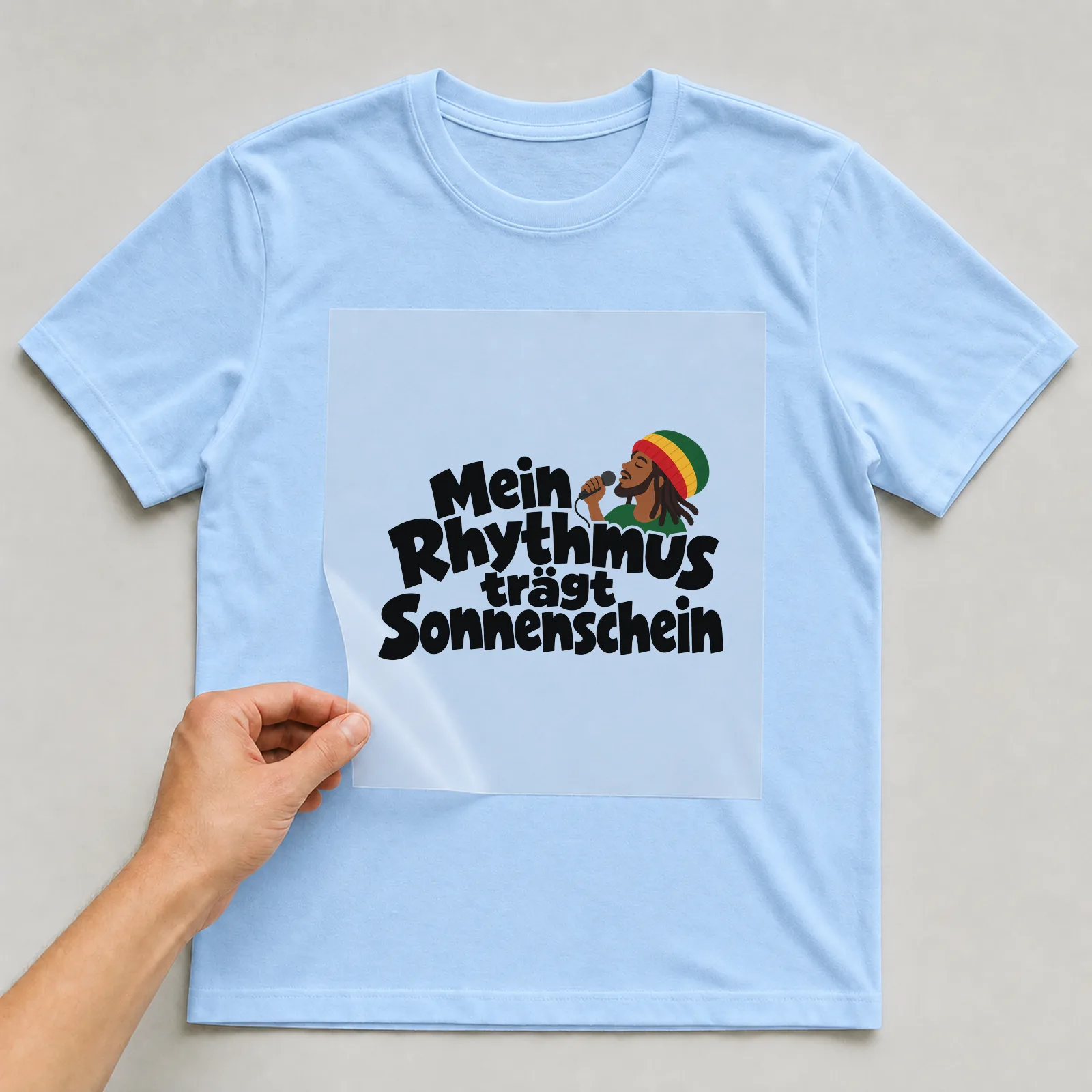 Bügelbild „Mein Rhythmus trägt Sonnenschein“ auf hellblauem T-Shirt, Folie wird aufgelegt
