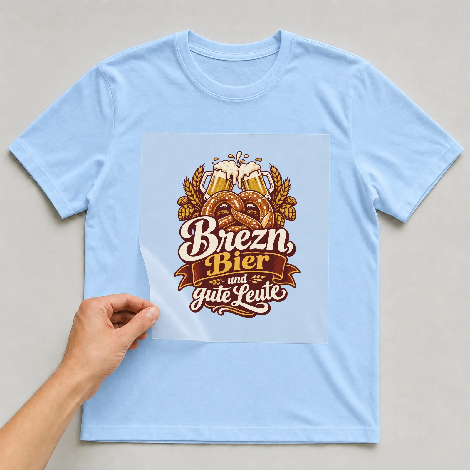 Bügelbild Brezn, Bier und gute Leute auf hellblauem T-Shirt, Folie wird aufgelegt