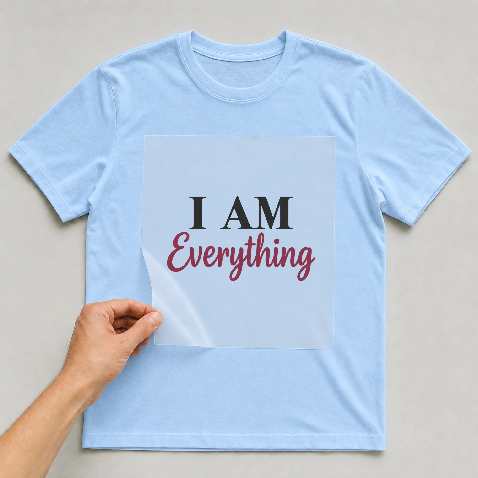 Bügelbild „I AM Everything“ auf babyblauem T-Shirt, Folie wird aufgelegt
