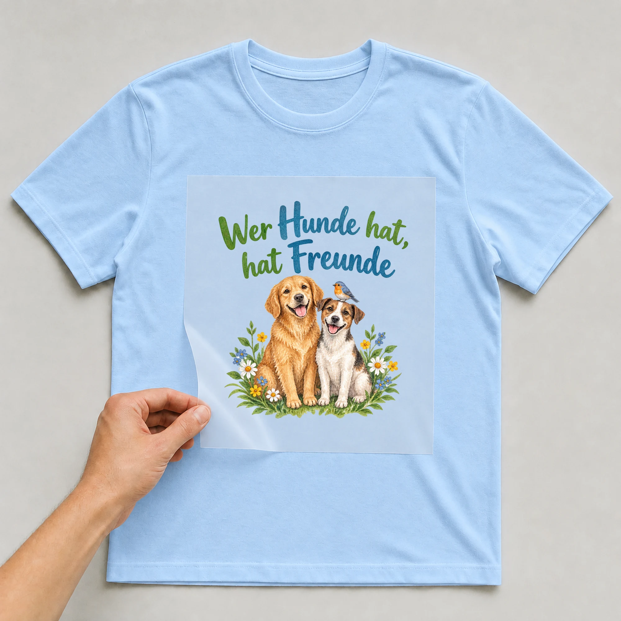 Bügelbild „Wer Hunde hat, hat Freunde“ auf babyblauem T-Shirt, Folie wird aufgelegt