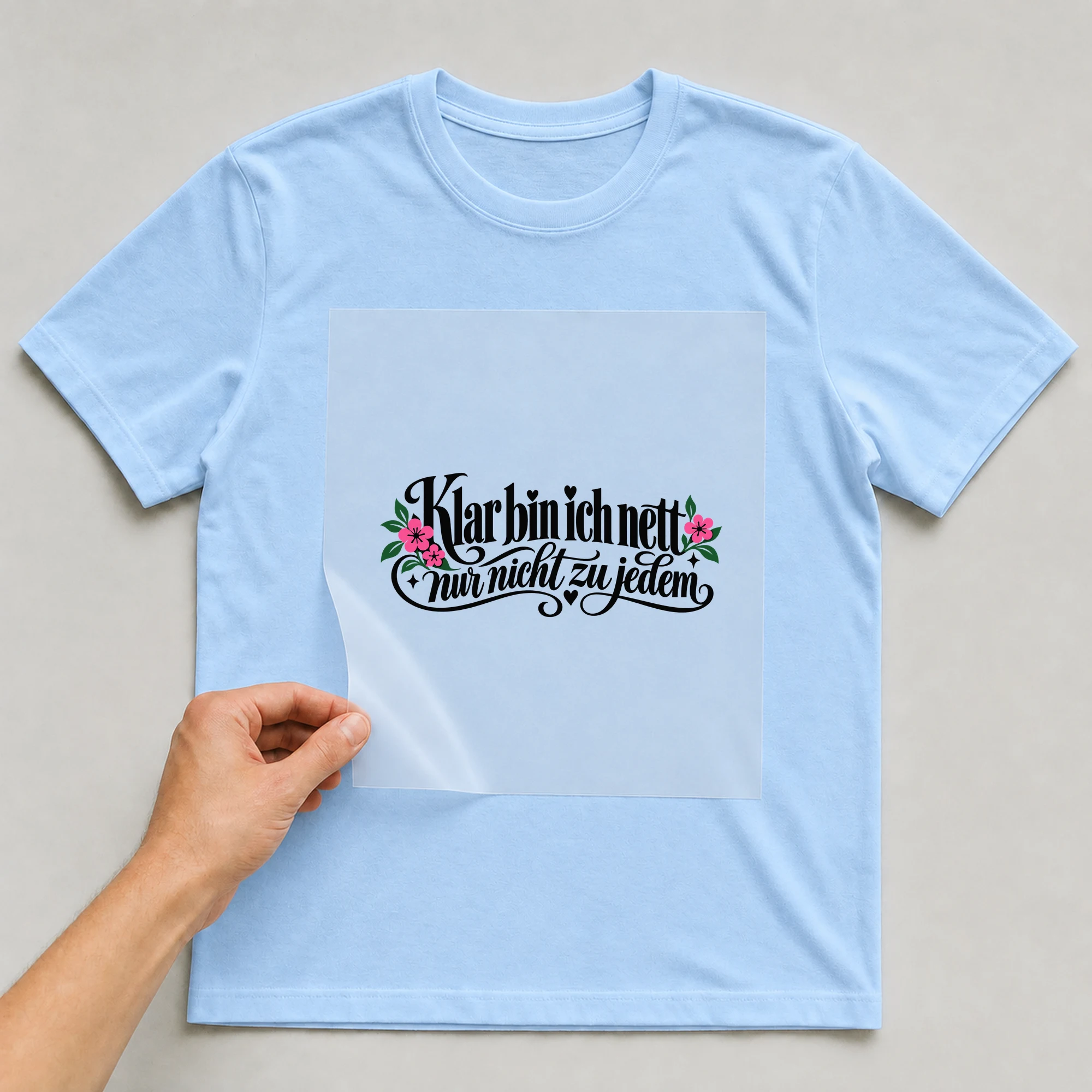 Bügelbild „Klar bin ich nett, nur nicht zu jedem“ auf babyblauem T-Shirt, Folie wird aufgelegt