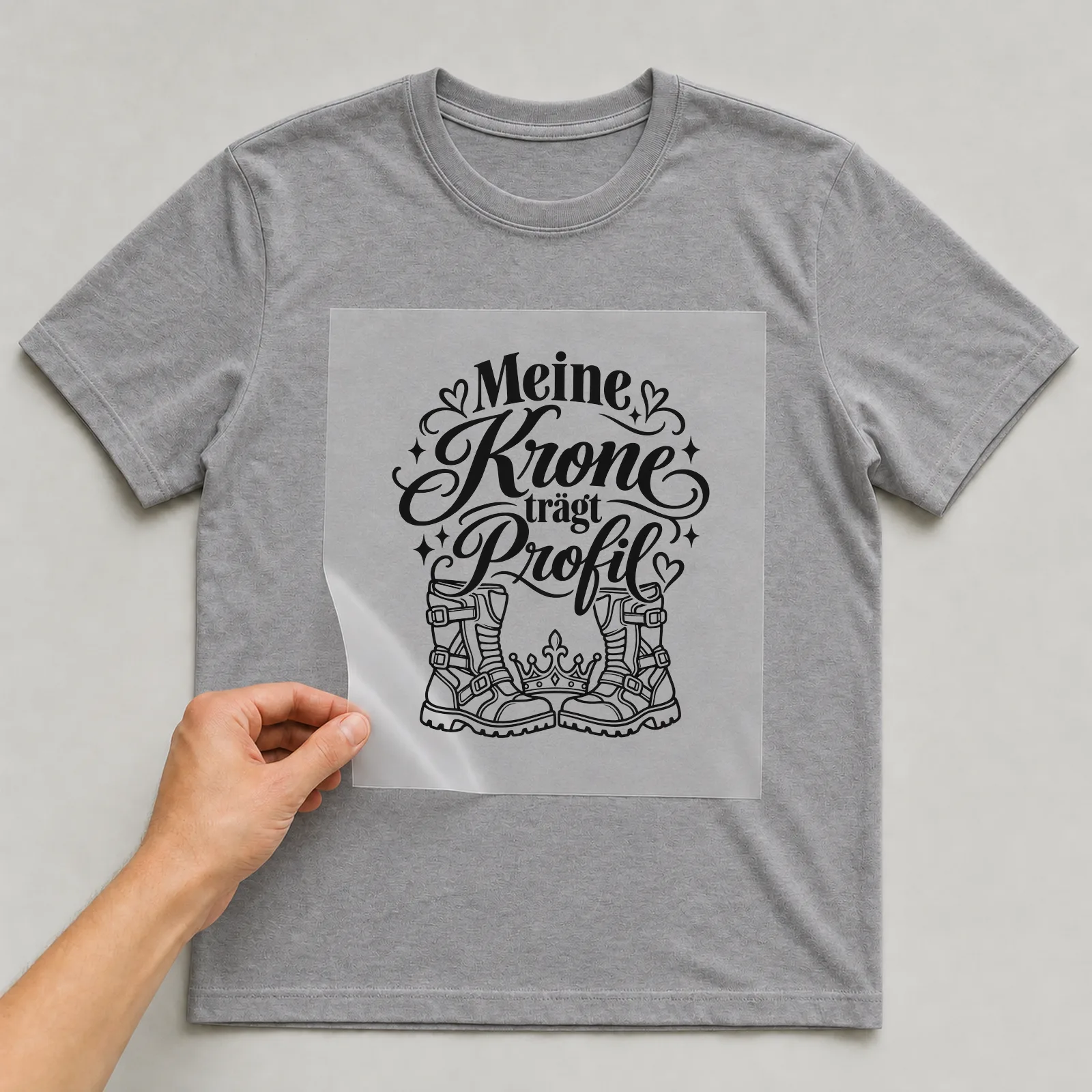 Bügelbild „Meine Krone trägt Profil“ auf grauem T-Shirt, Folie wird aufgelegt