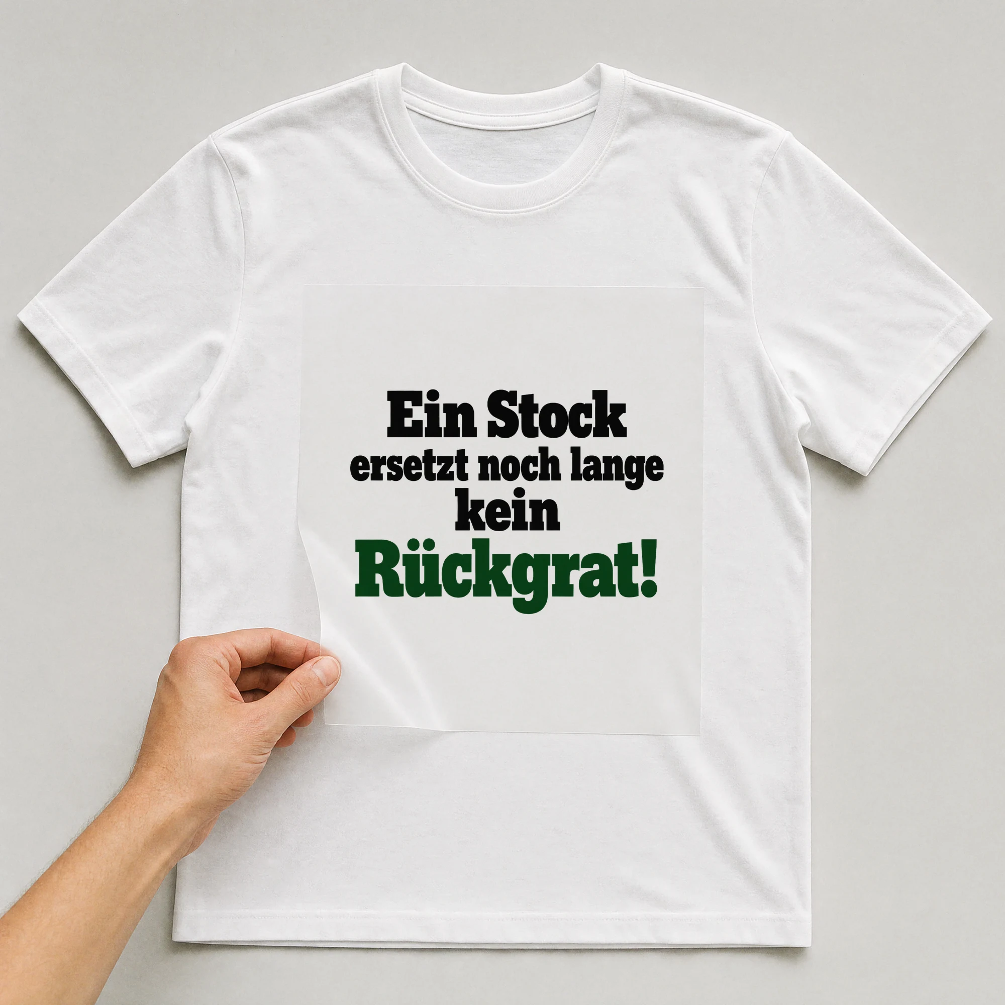 Bügelbild „Ein Stock ersetzt noch lange kein Rückgrat!“ auf weißem T-Shirt, Folie wird aufgelegt