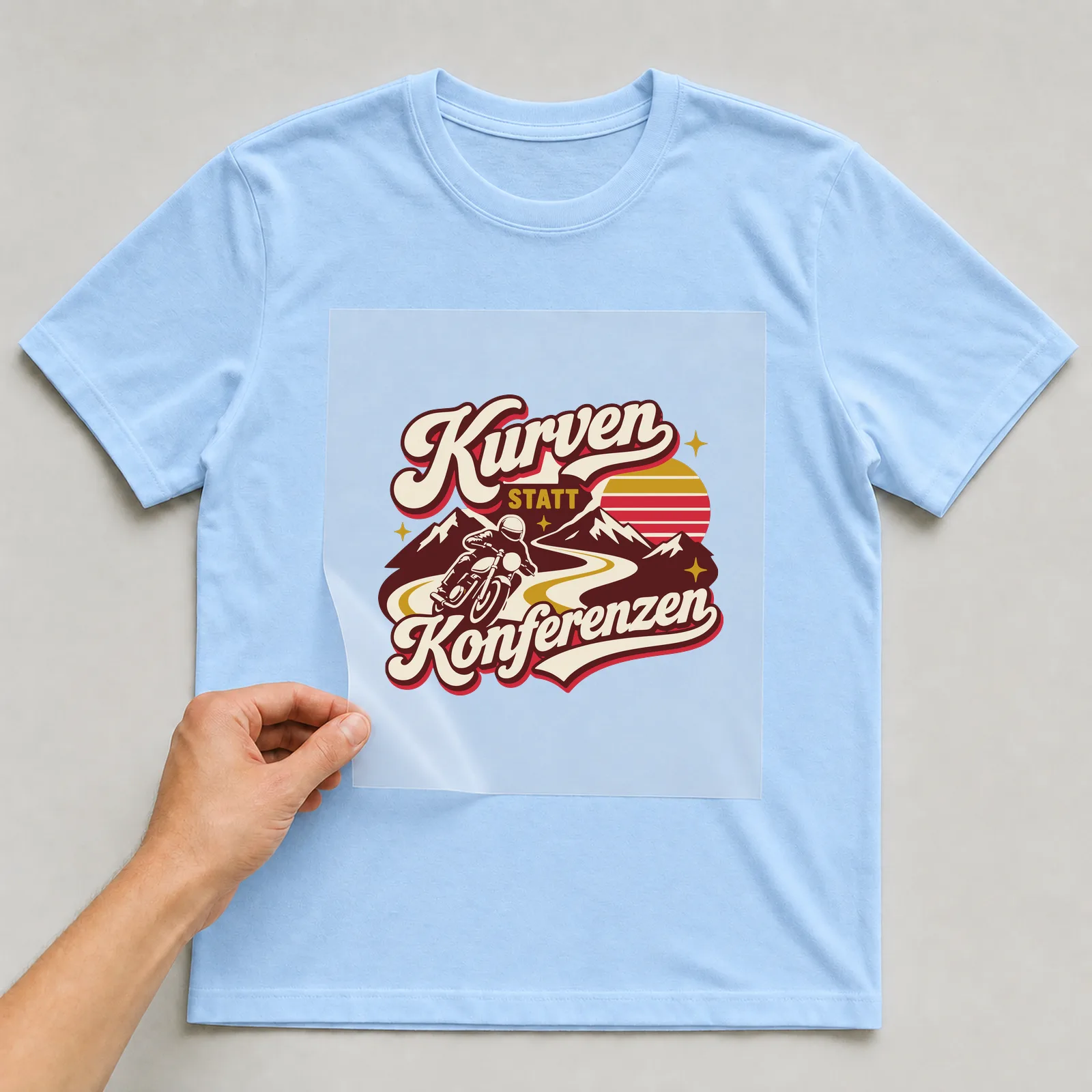 Bügelbild Kurven statt Konferenzen auf hellblauem T-Shirt, Folie wird aufgelegt