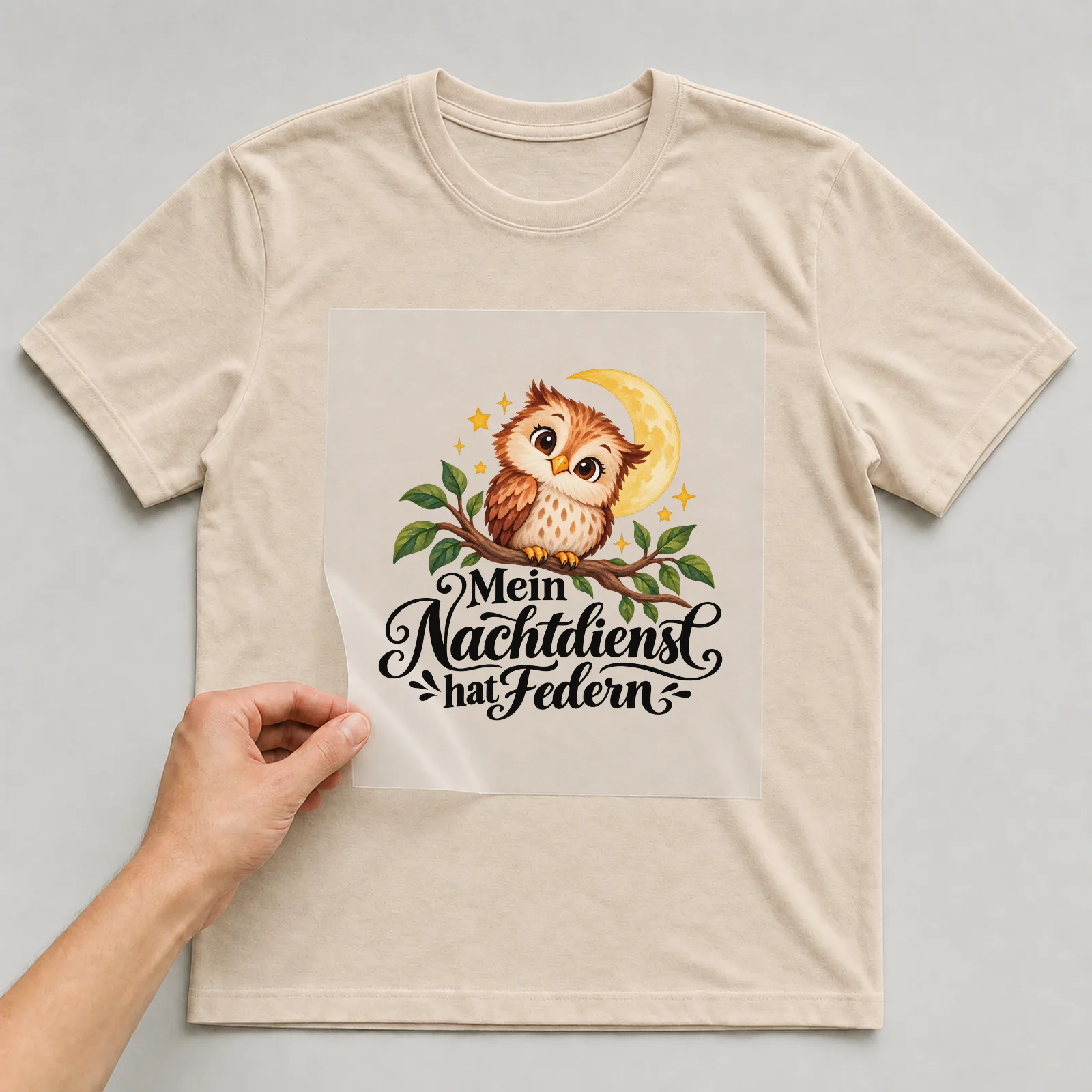 Bügelbild „Mein Nachtdienst hat Federn“ auf beigem T-Shirt, Folie wird aufgelegt