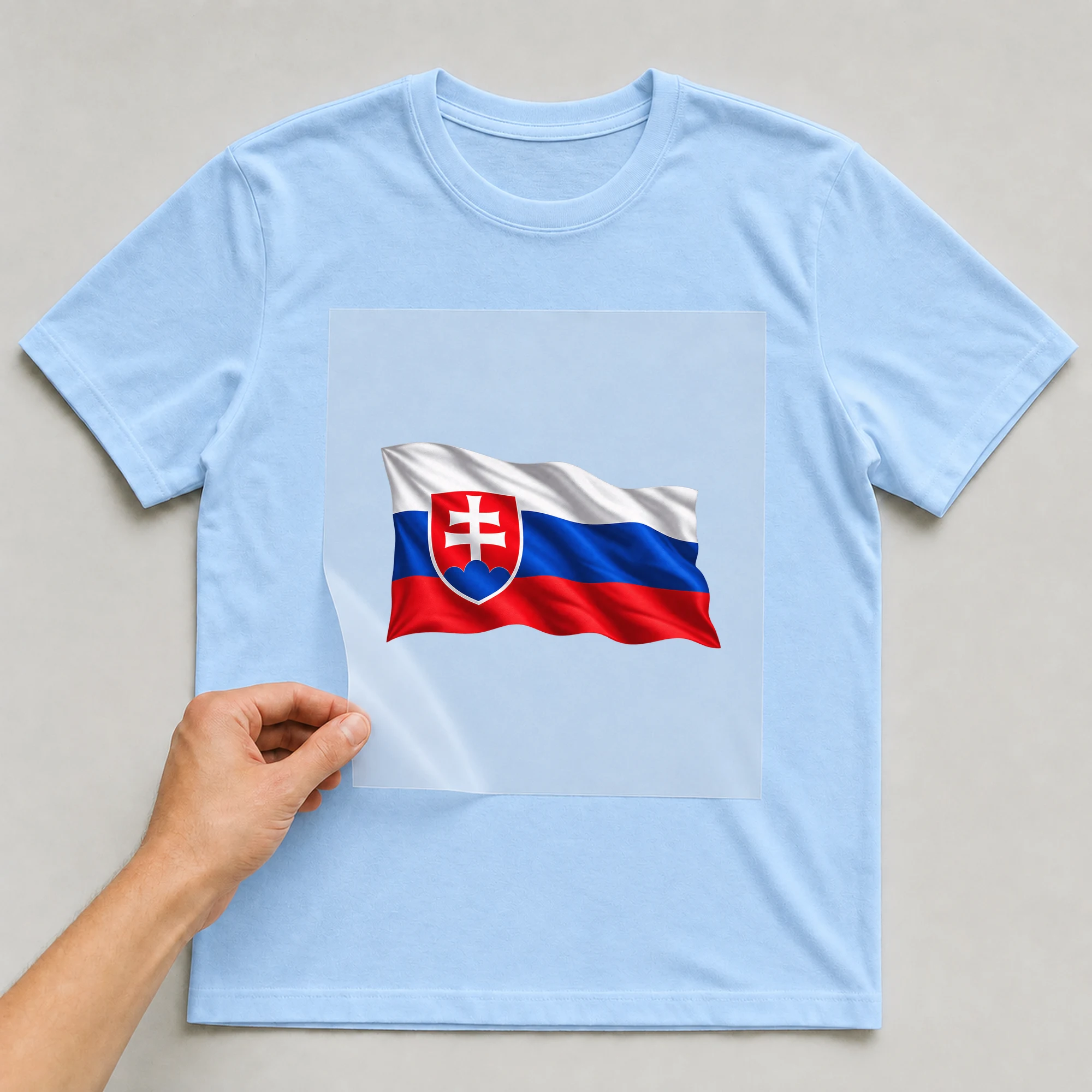 Bügelbild „Länder Flagge Slowakei“ auf babyblauem T-Shirt, Folie wird aufgelegt
