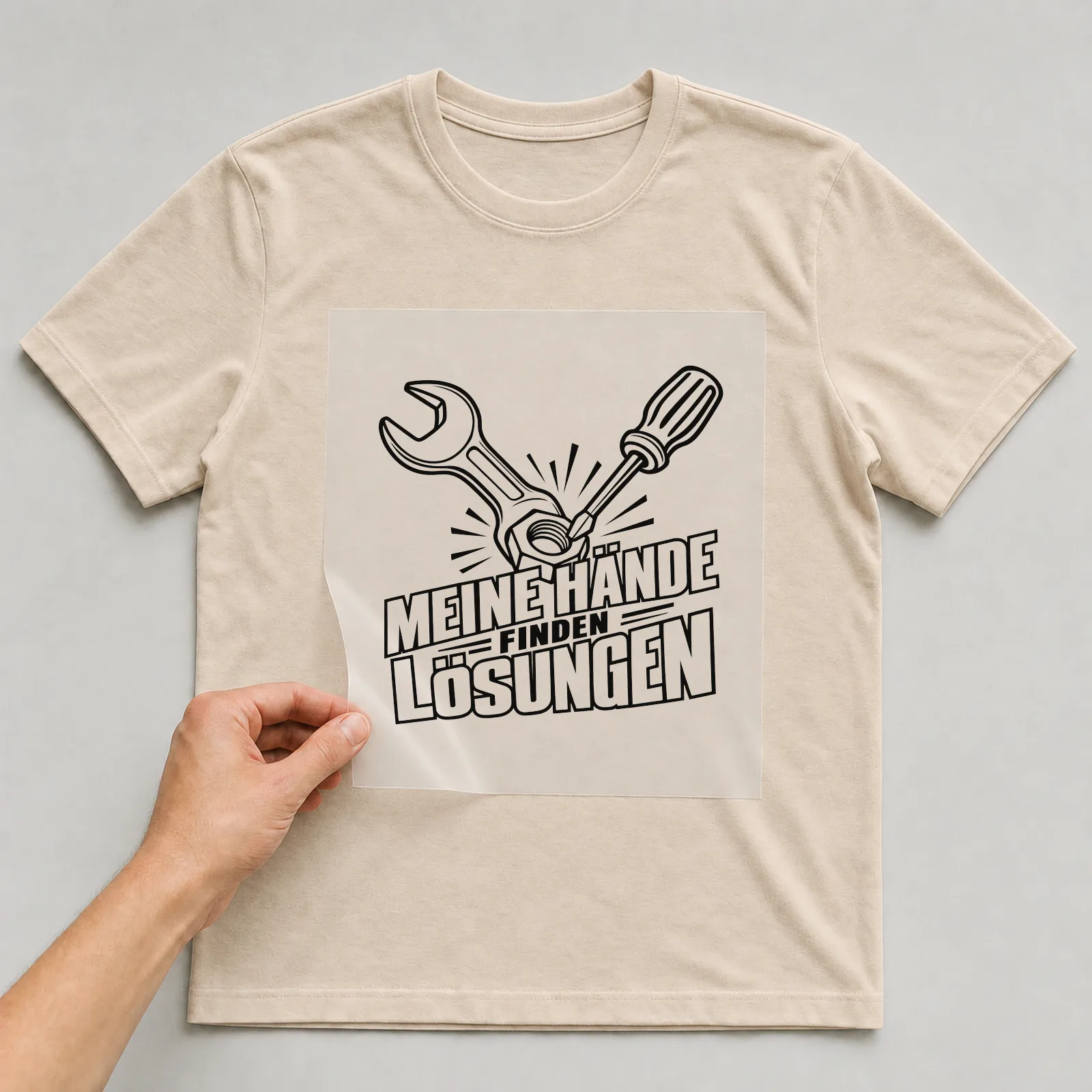 Bügelbild „Meine Hände finden Lösungen“ auf beigem T-Shirt, Folie wird aufgelegt