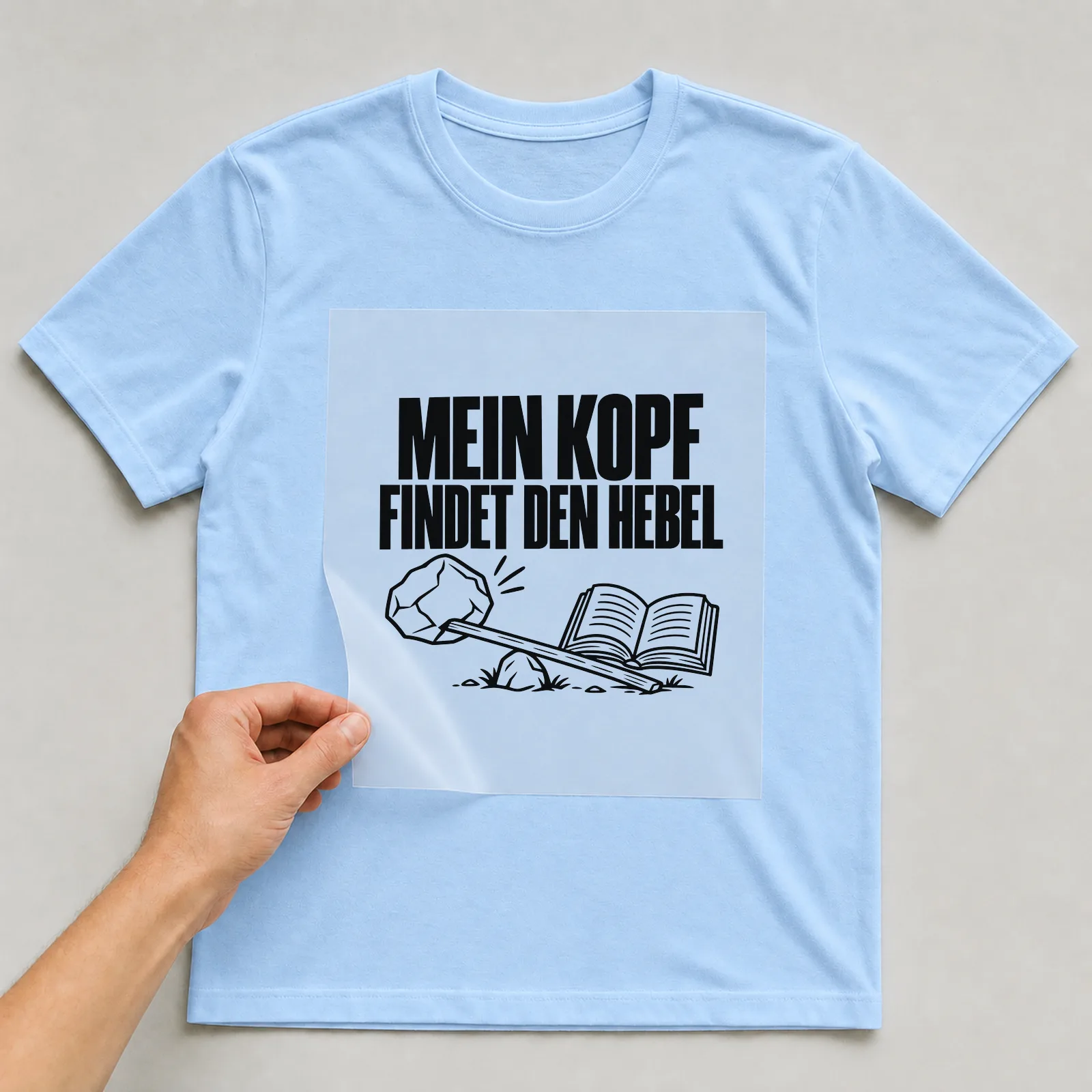 Bügelbild „Mein Kopf findet den Hebel“ auf hellblauem T-Shirt, Folie wird aufgelegt