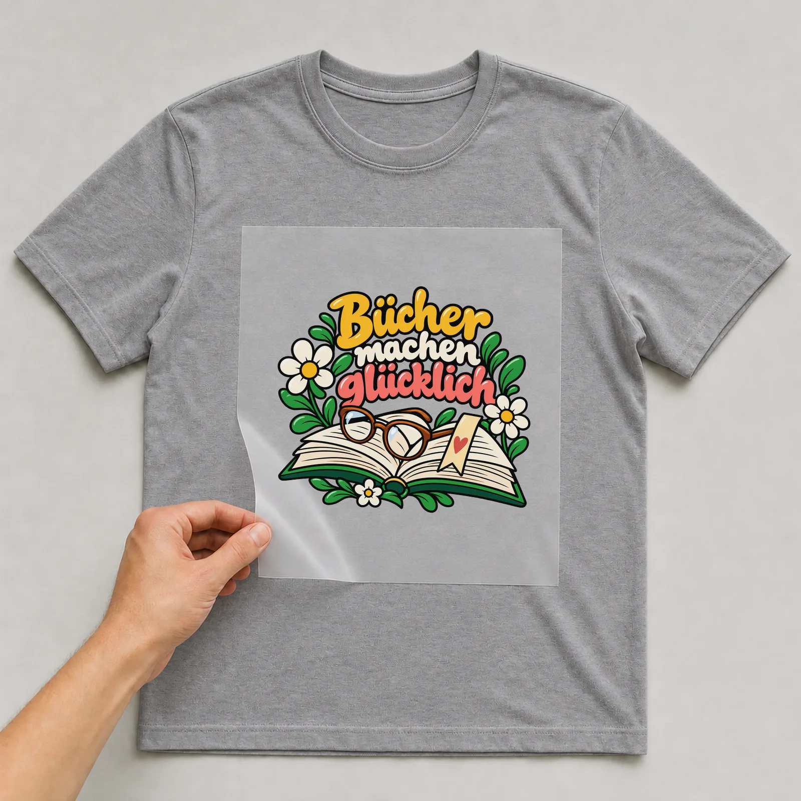 Bügelbild „Bücher machen glücklich“ auf grauem T-Shirt, Folie wird aufgelegt