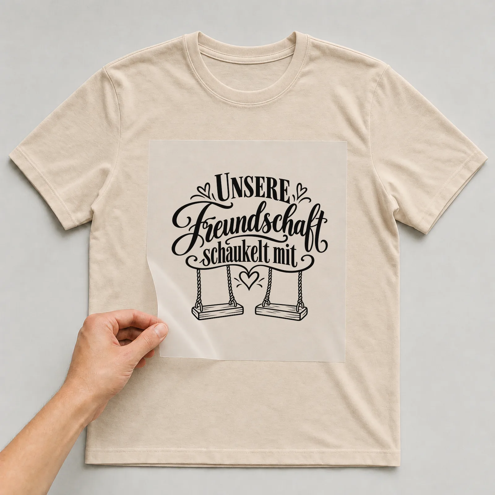 Bügelbild „Unsere Freundschaft schaukelt mit“ auf beigem T-Shirt, Folie wird aufgelegt