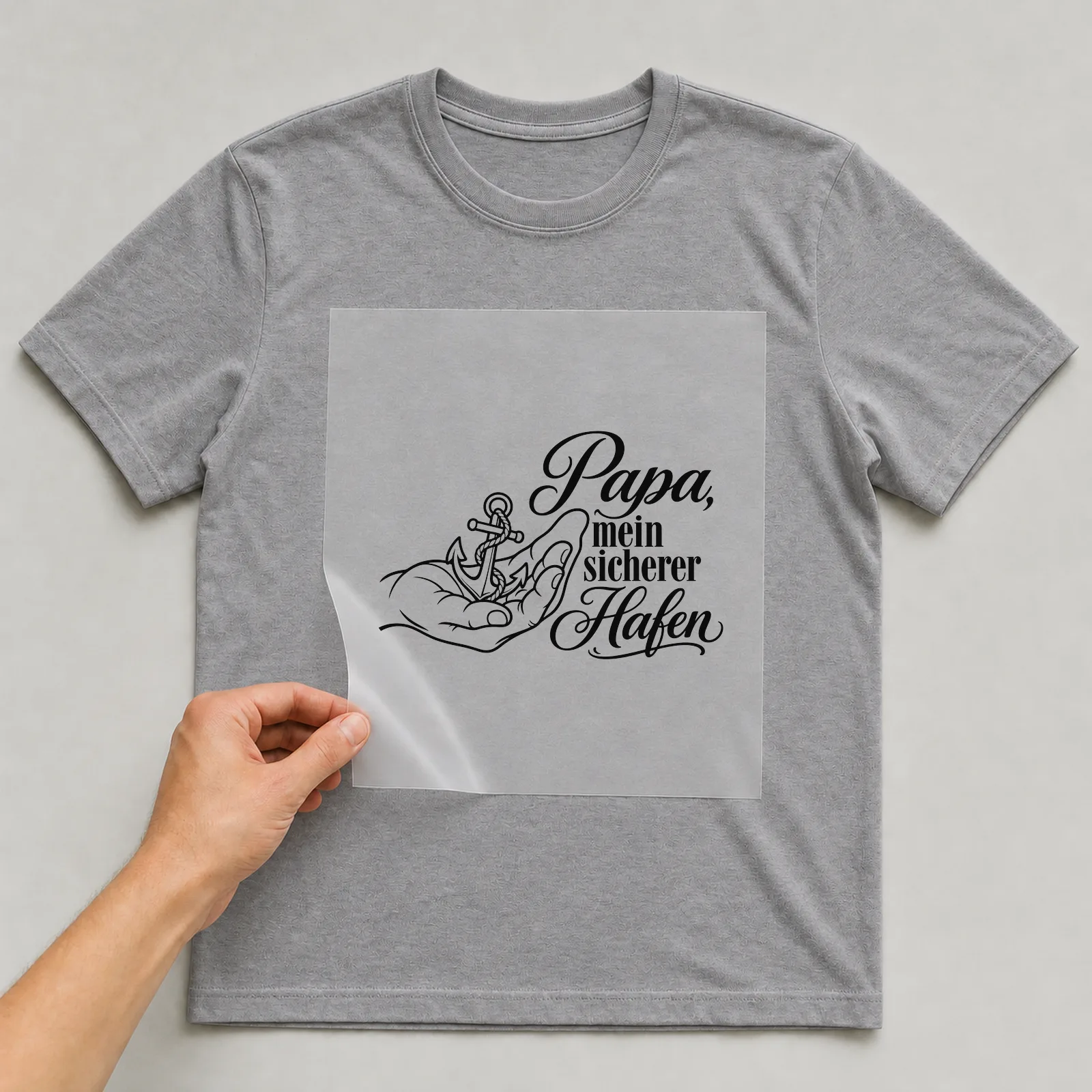 Bügelbild „Papa, mein sicherer Hafen“ auf grauem T-Shirt, Folie wird aufgelegt