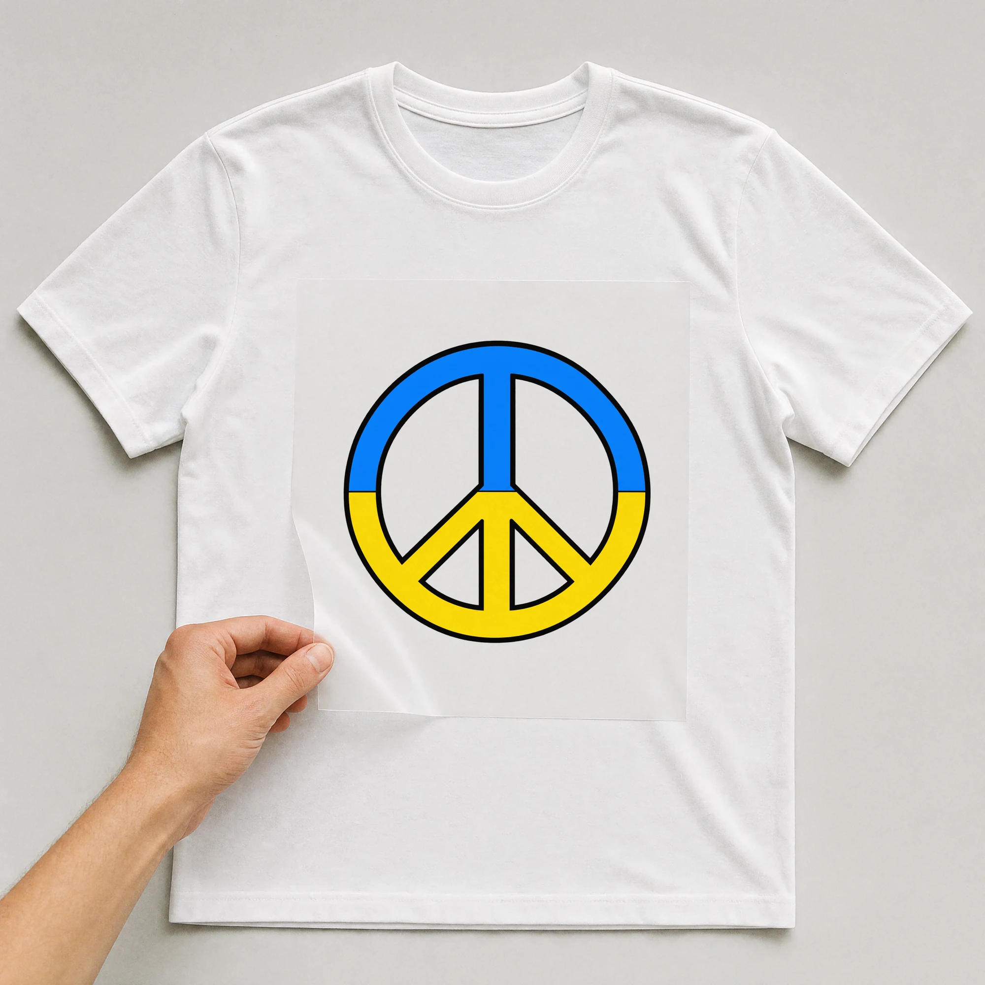Bügelbild „Peace Flagge Ukraine“ auf weißem T-Shirt, Folie wird aufgelegt