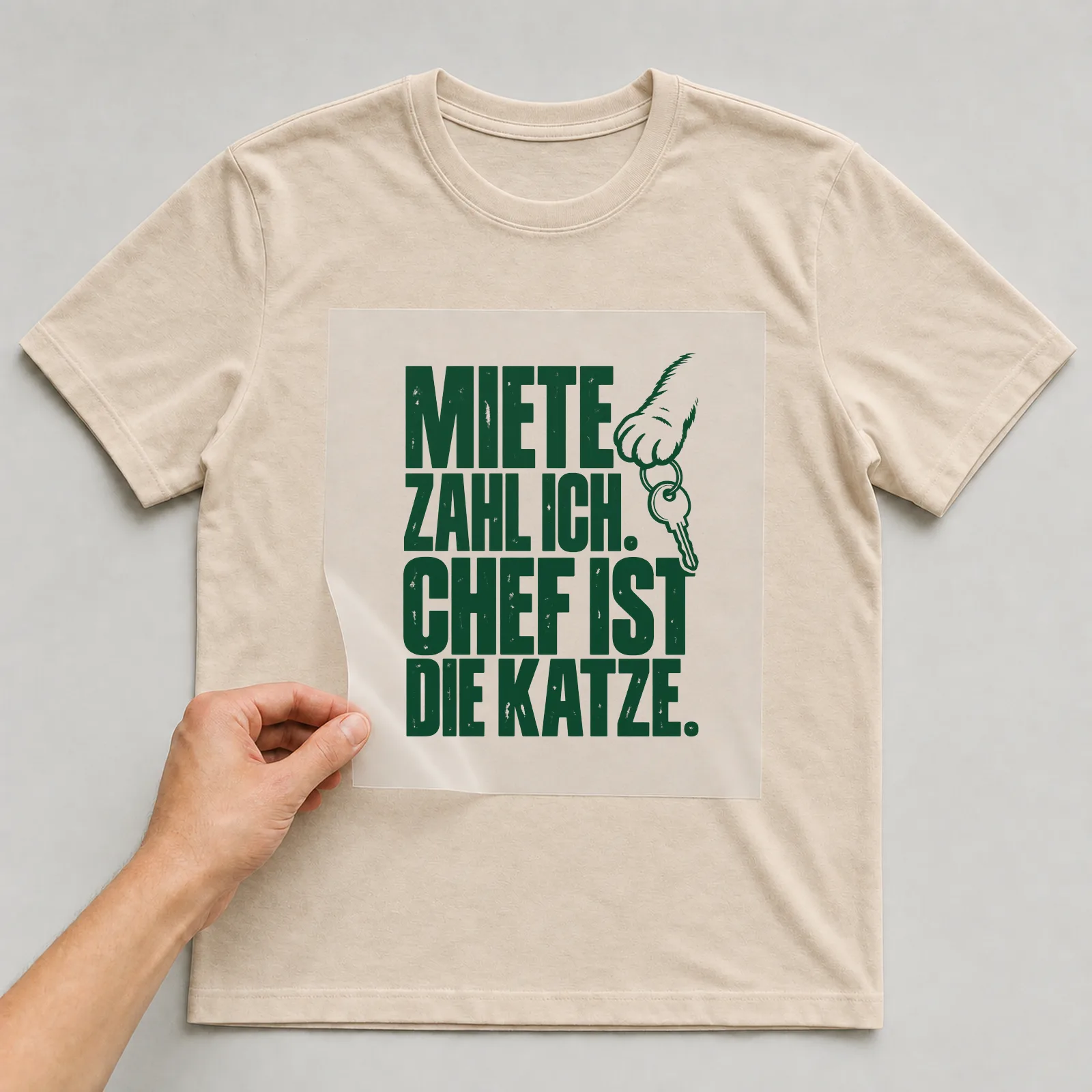 Bügelbild „Miete zahl ich. Chef ist die Katze.“ auf beigem T-Shirt, Folie wird aufgelegt