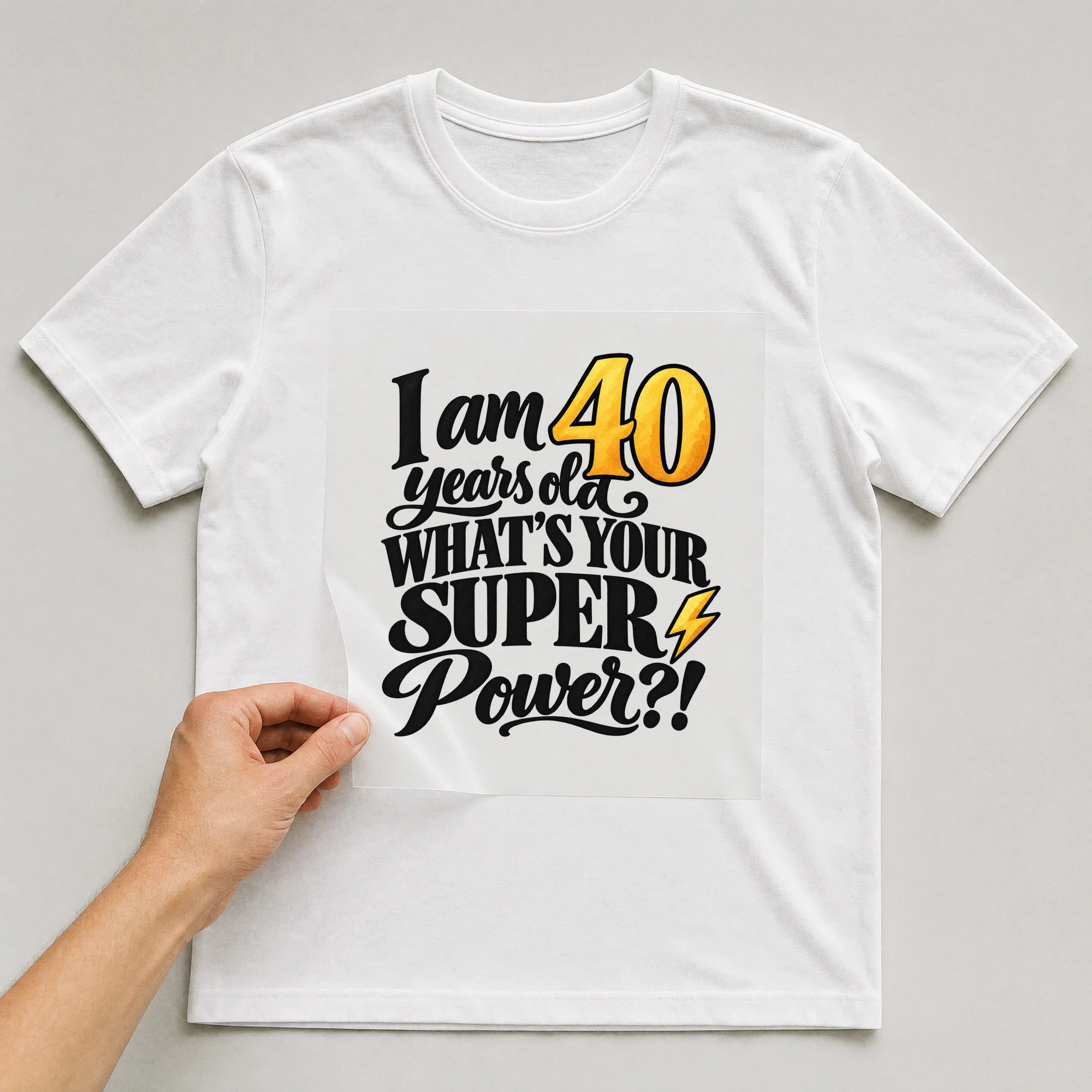 Bügelbild „I Am 40 Years Old What's Your Super Power?!“ auf weißem T-Shirt, Folie wird aufgelegt
