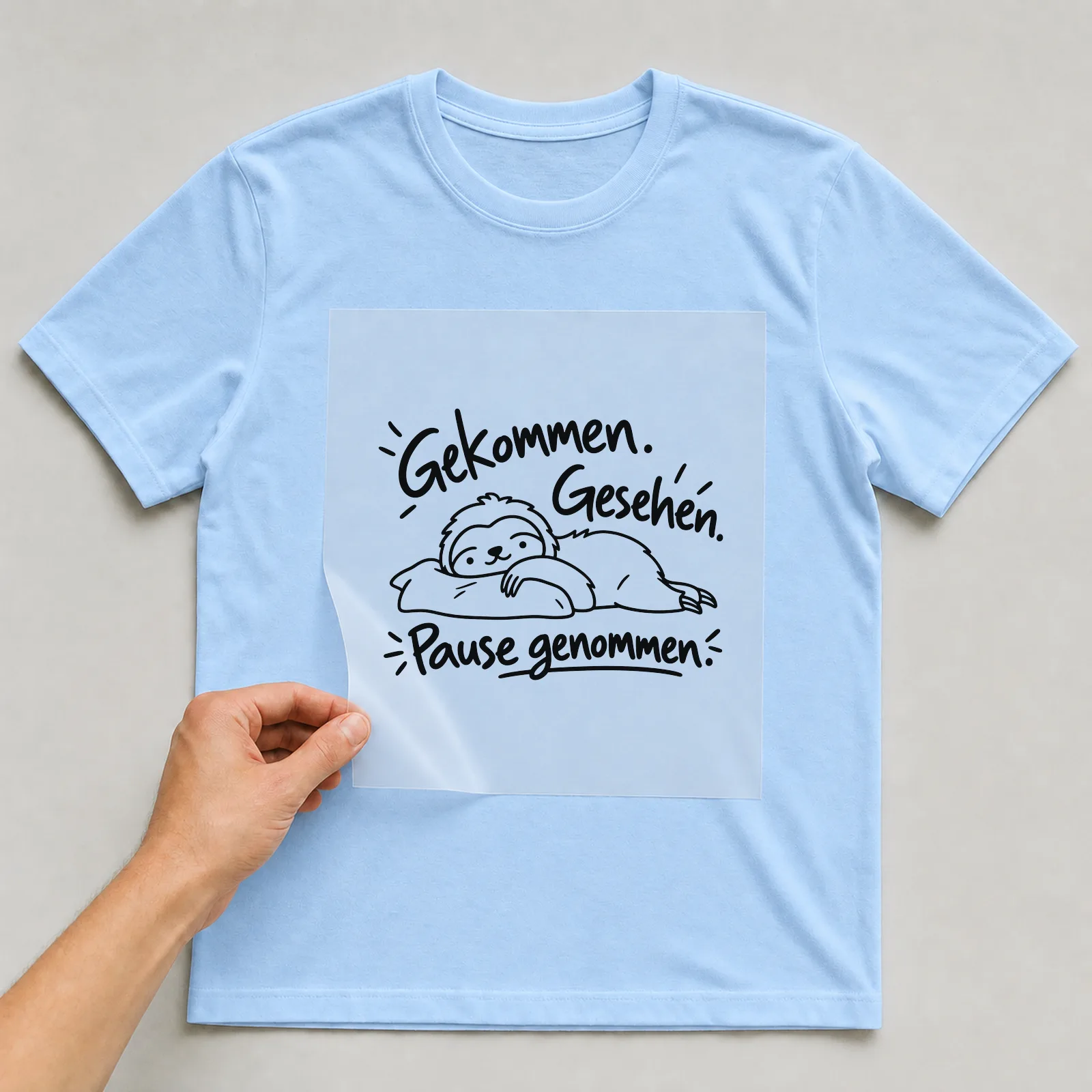 Bügelbild „Gekommen. Gesehen. Pause genommen.“ auf hellblauem T-Shirt, Folie wird aufgelegt