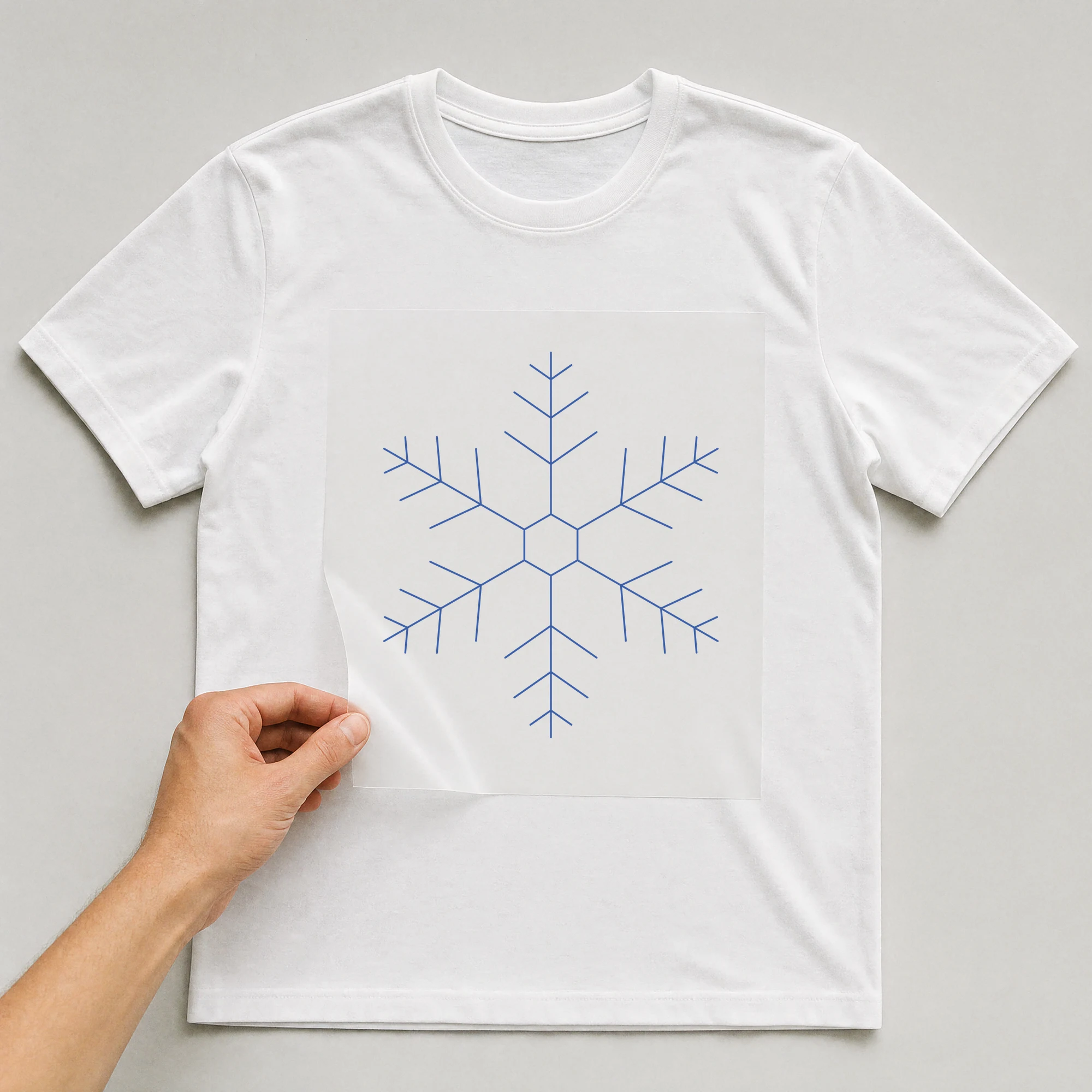 Bügelbild „Schneeflocke“ auf weißem T-Shirt, Folie wird aufgelegt