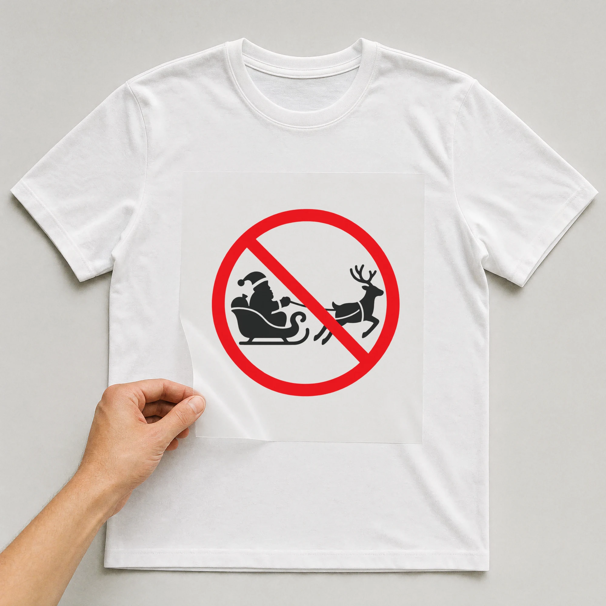 Bügelbild „Weihnachtsmann-Schlitten im Verbotsschild“ auf weißem T-Shirt, Folie wird aufgelegt