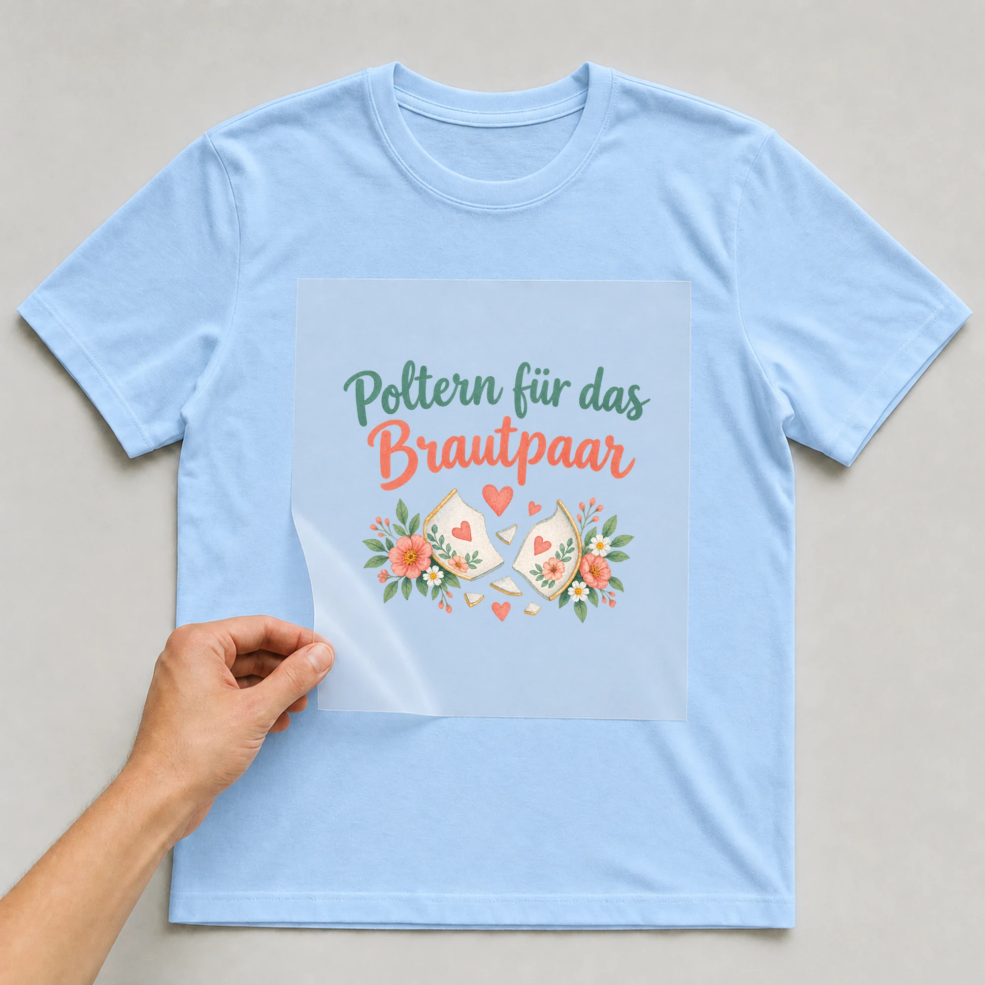 Bügelbild „Poltern für das Brautpaar“ auf babyblauem T-Shirt, Folie wird aufgelegt