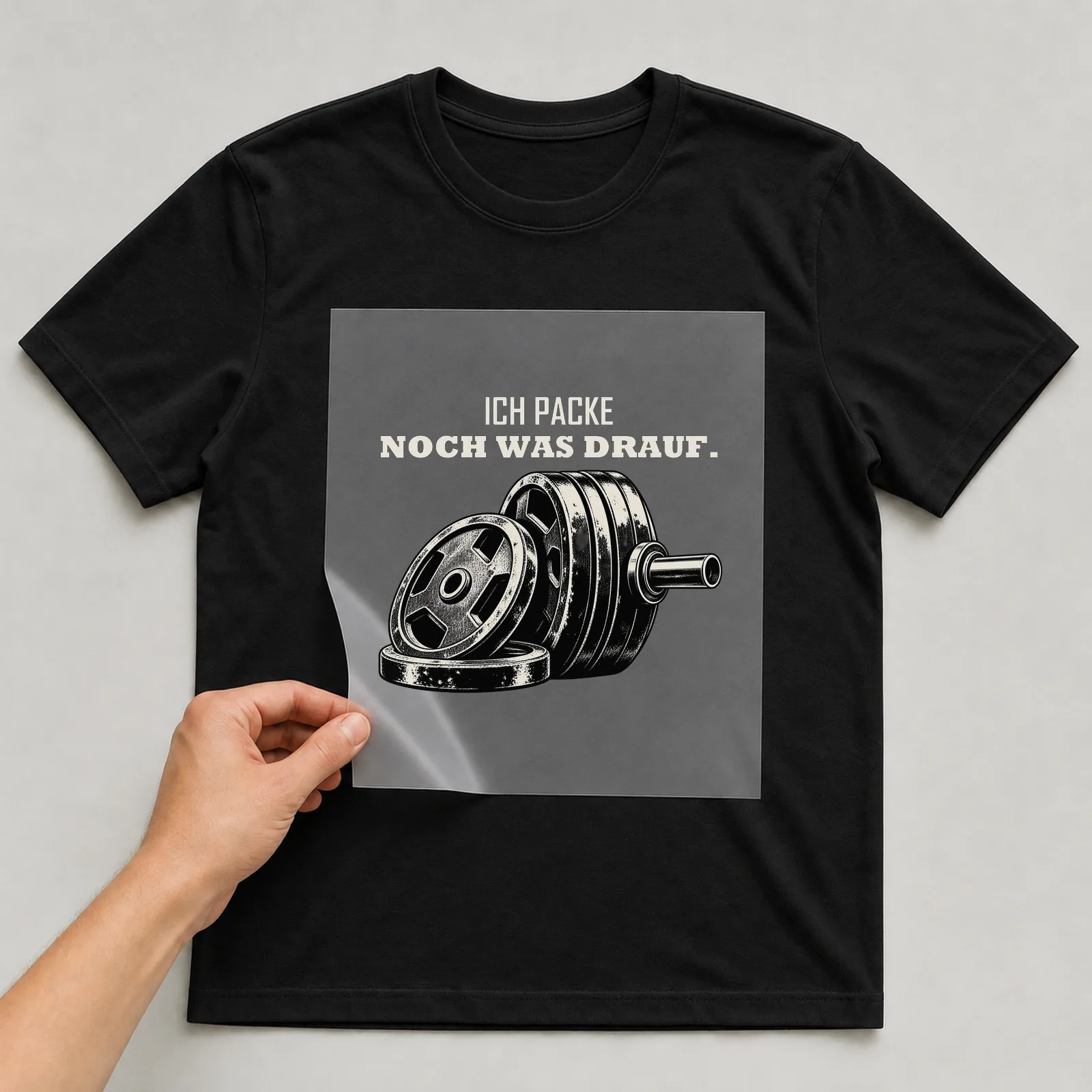 Bügelbild „Ich packe noch was drauf“ auf schwarzem T-Shirt, Folie wird aufgelegt