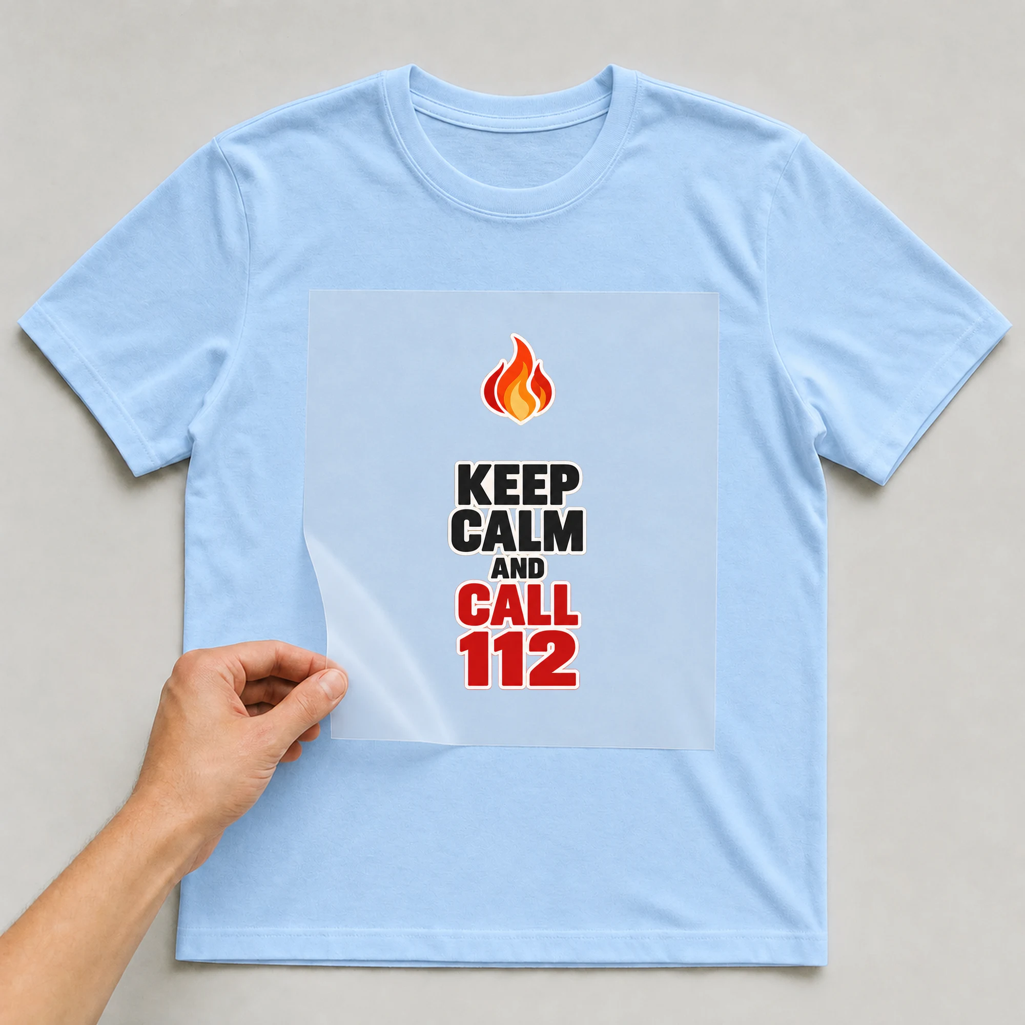 Bügelbild „KEEP CALM AND CALL 112“ auf babyblauem T-Shirt, Folie wird aufgelegt