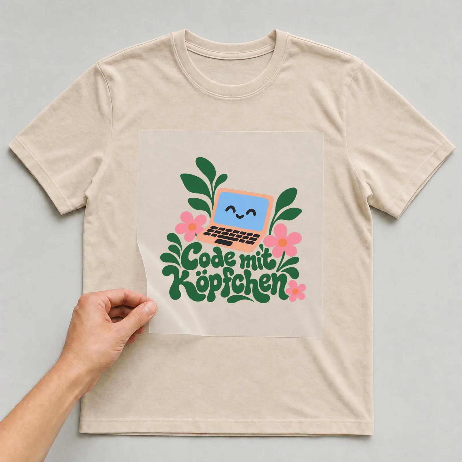 Bügelbild „Code mit Köpfchen“ auf beigem T-Shirt, Folie wird aufgelegt