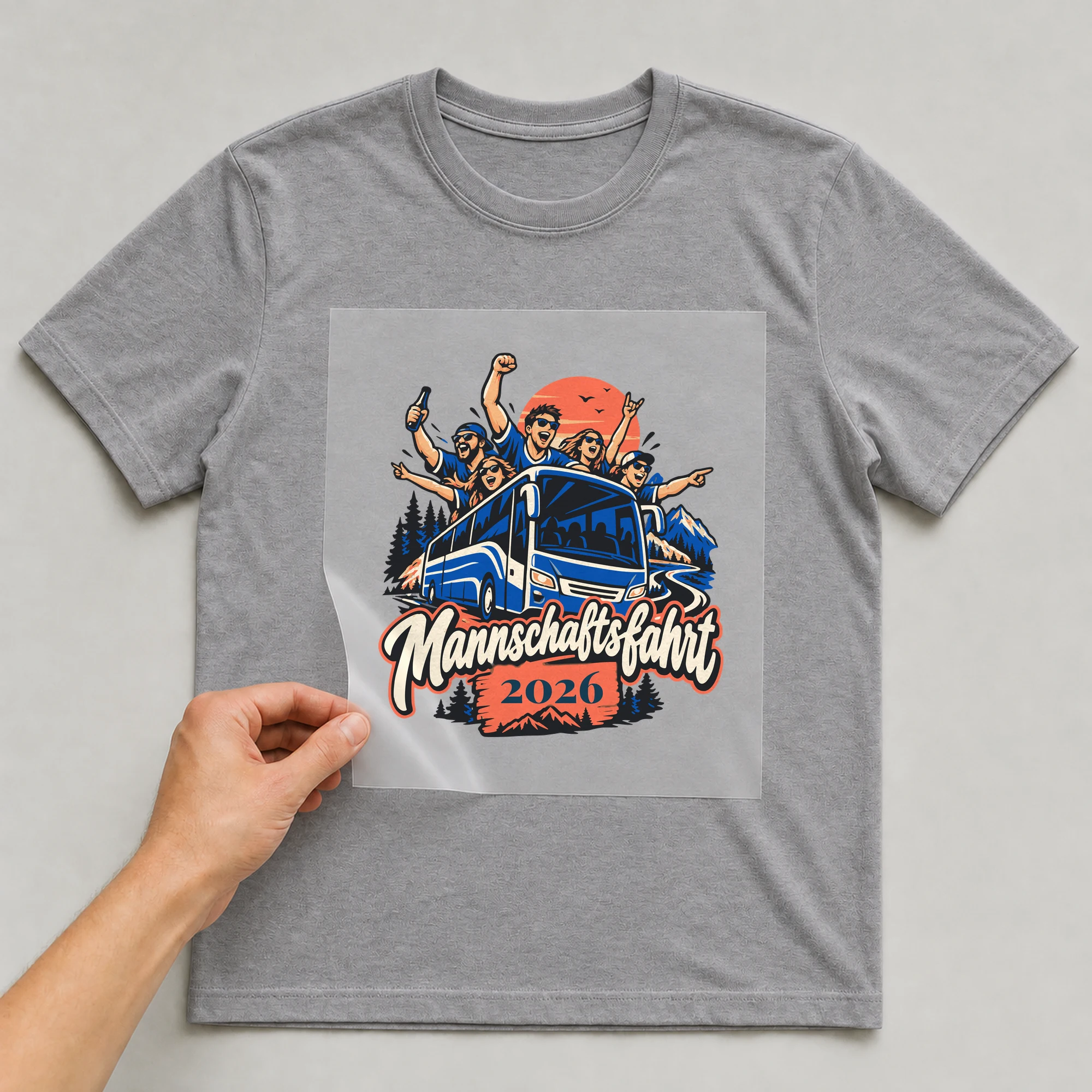 Bügelbild Mannschaftsfahrt mit Jahr auf grauem T-Shirt, Folie wird aufgelegt