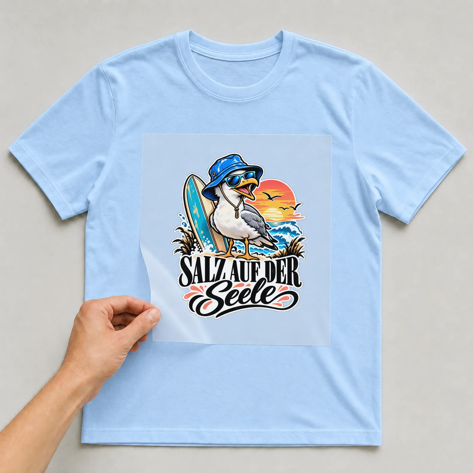 Bügelbild „Salz auf der Seele“ auf hellblauem T-Shirt, Folie wird aufgelegt