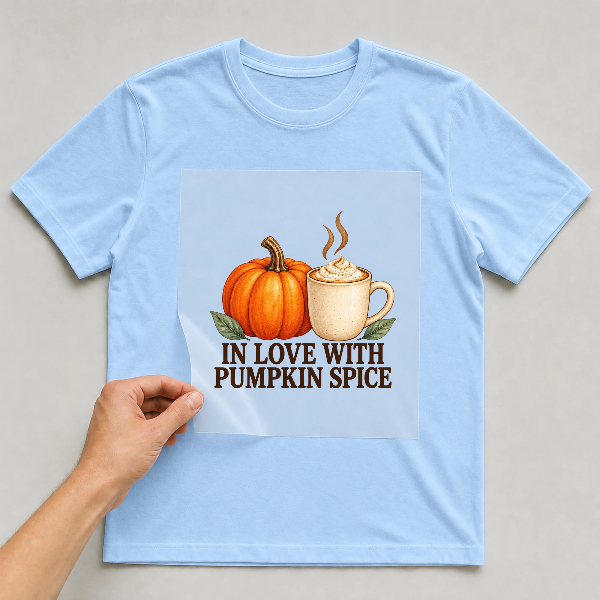 Bügelbild „IN LOVE WITH PUMPKIN SPICE“ auf babyblauem T-Shirt, Folie wird aufgelegt